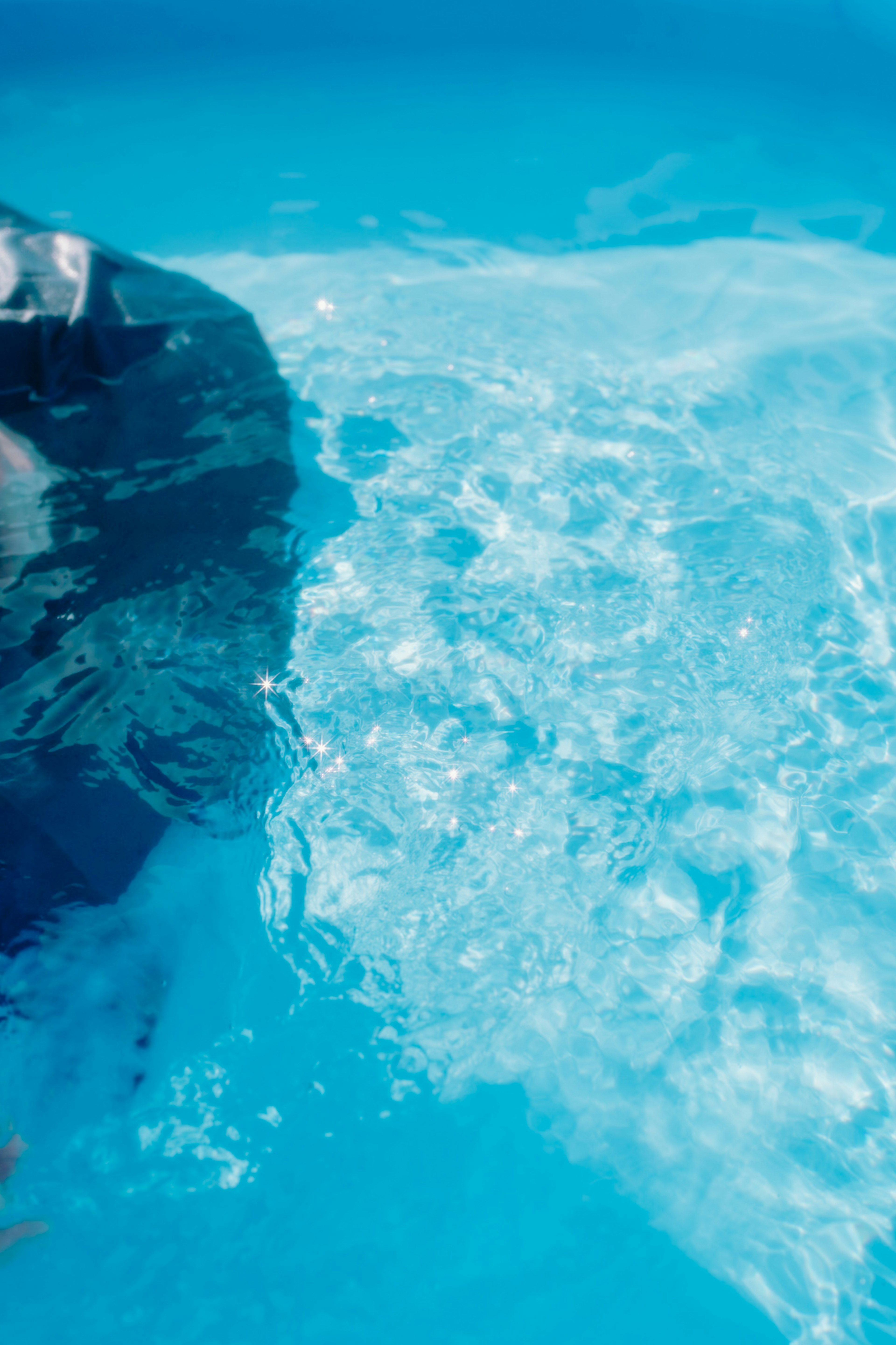 Surface d'eau ondulante d'une piscine bleue réfléchissant la lumière