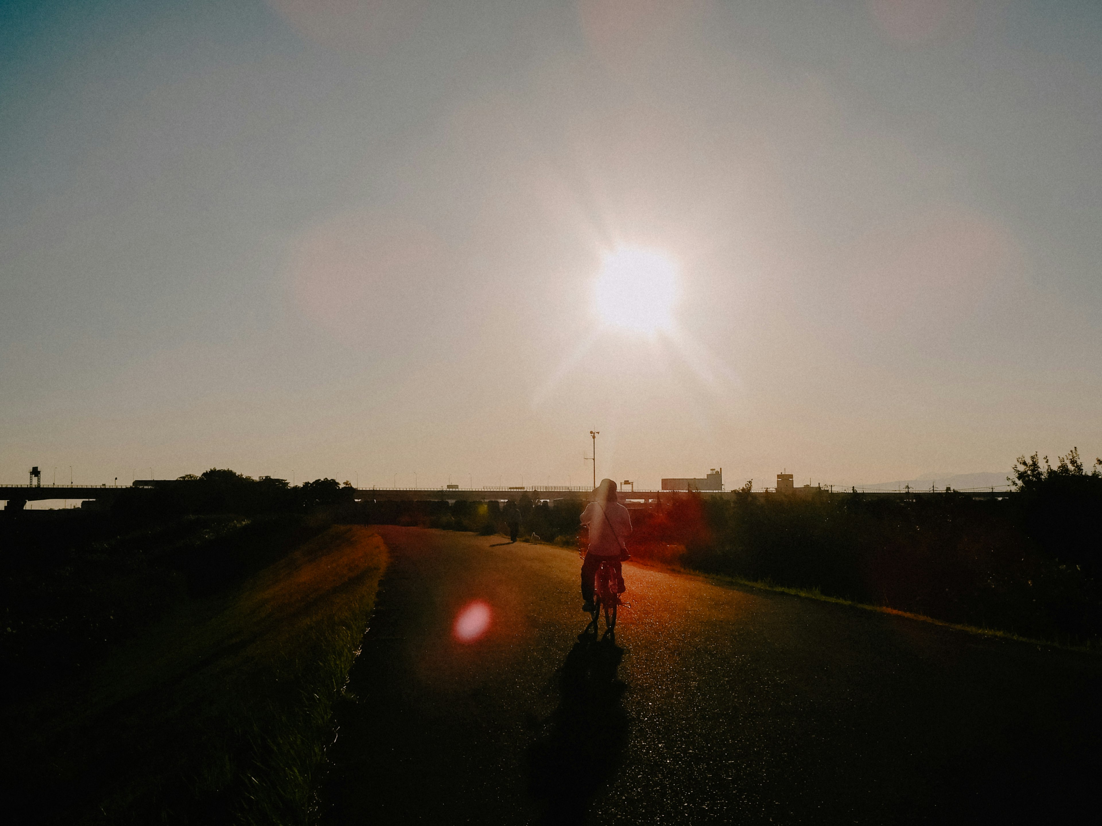 Una persona che pedala con il sole al tramonto sullo sfondo