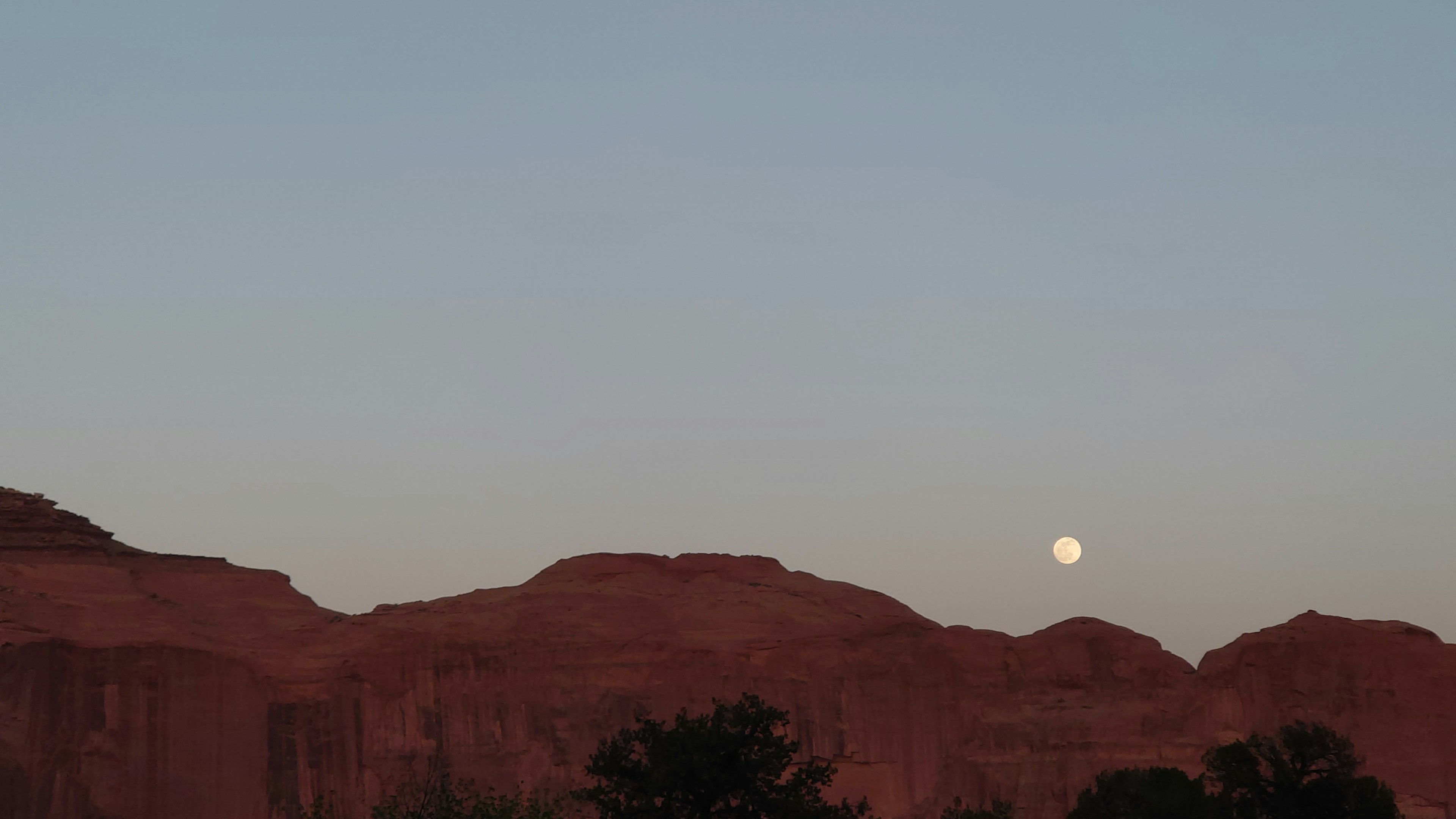 Paisaje de montañas de roca roja con luna creciente y cielo crepuscular