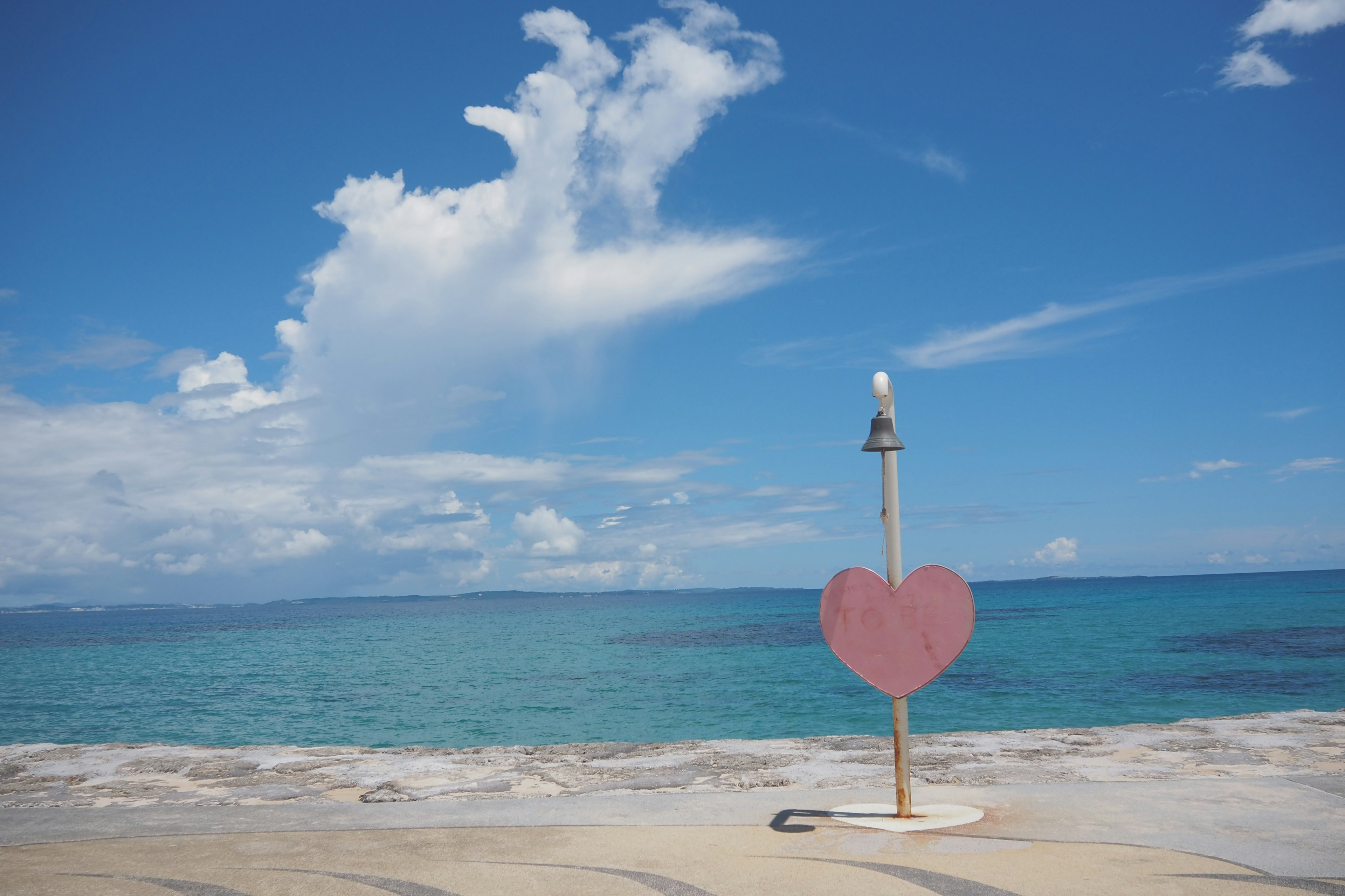 Escultura en forma de corazón junto al mar azul y al cielo