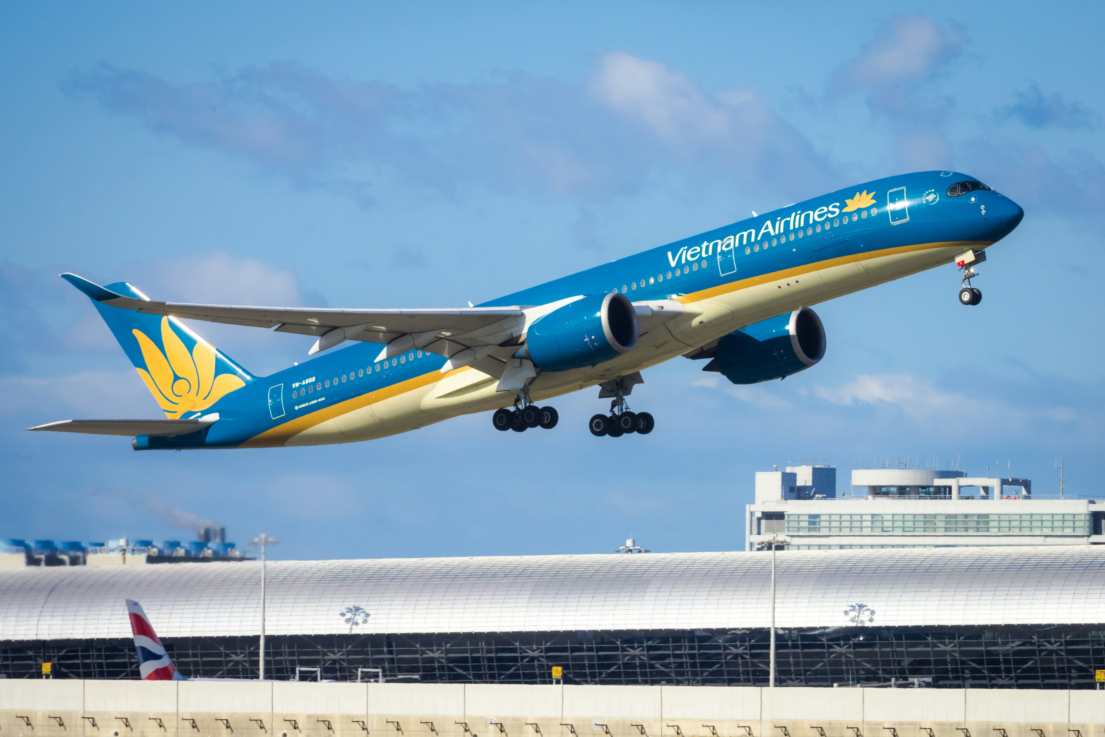 Blue aircraft taking off against a clear sky at an airport