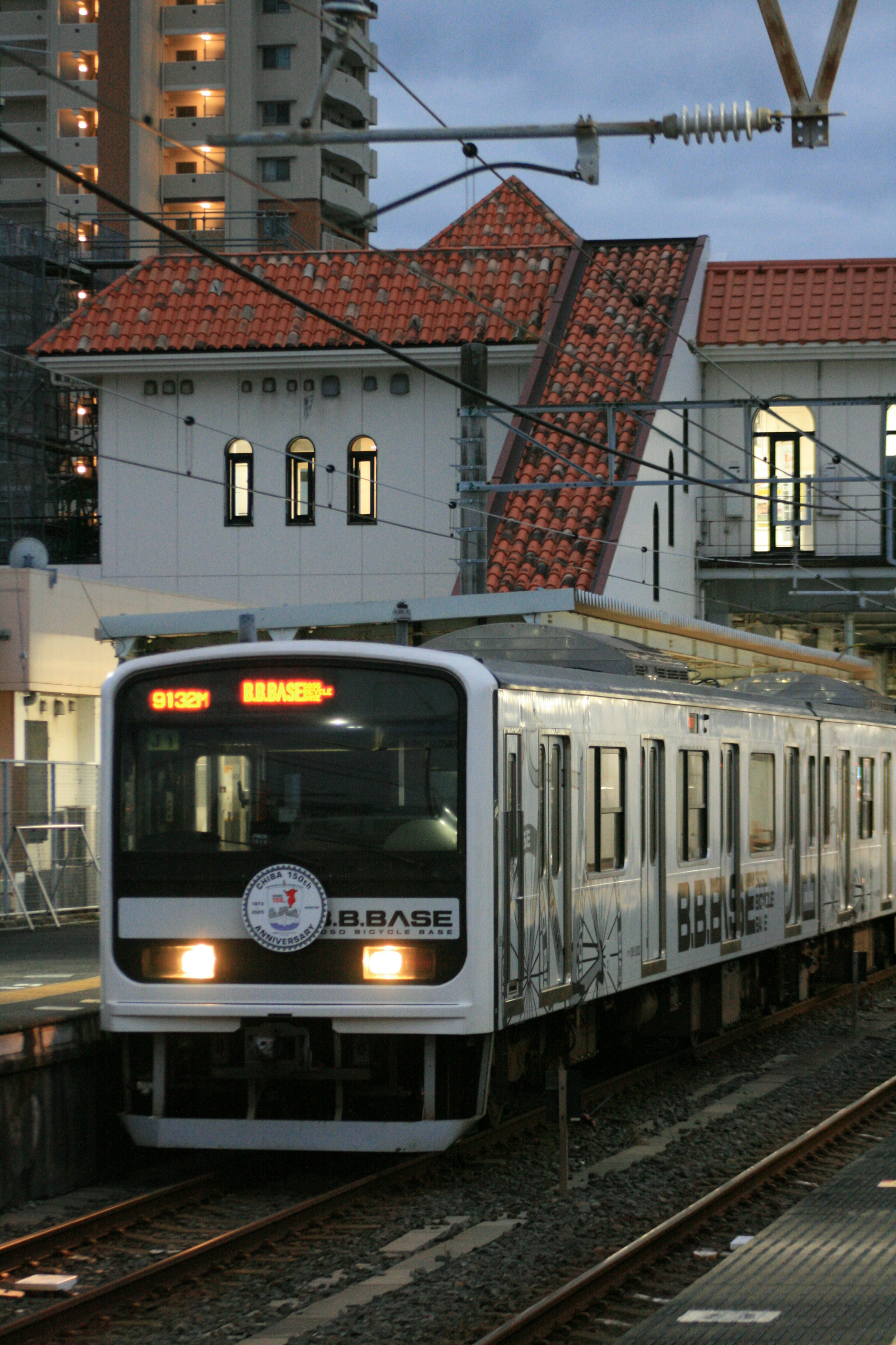 Kereta putih di stasiun dengan bangunan atap merah saat senja