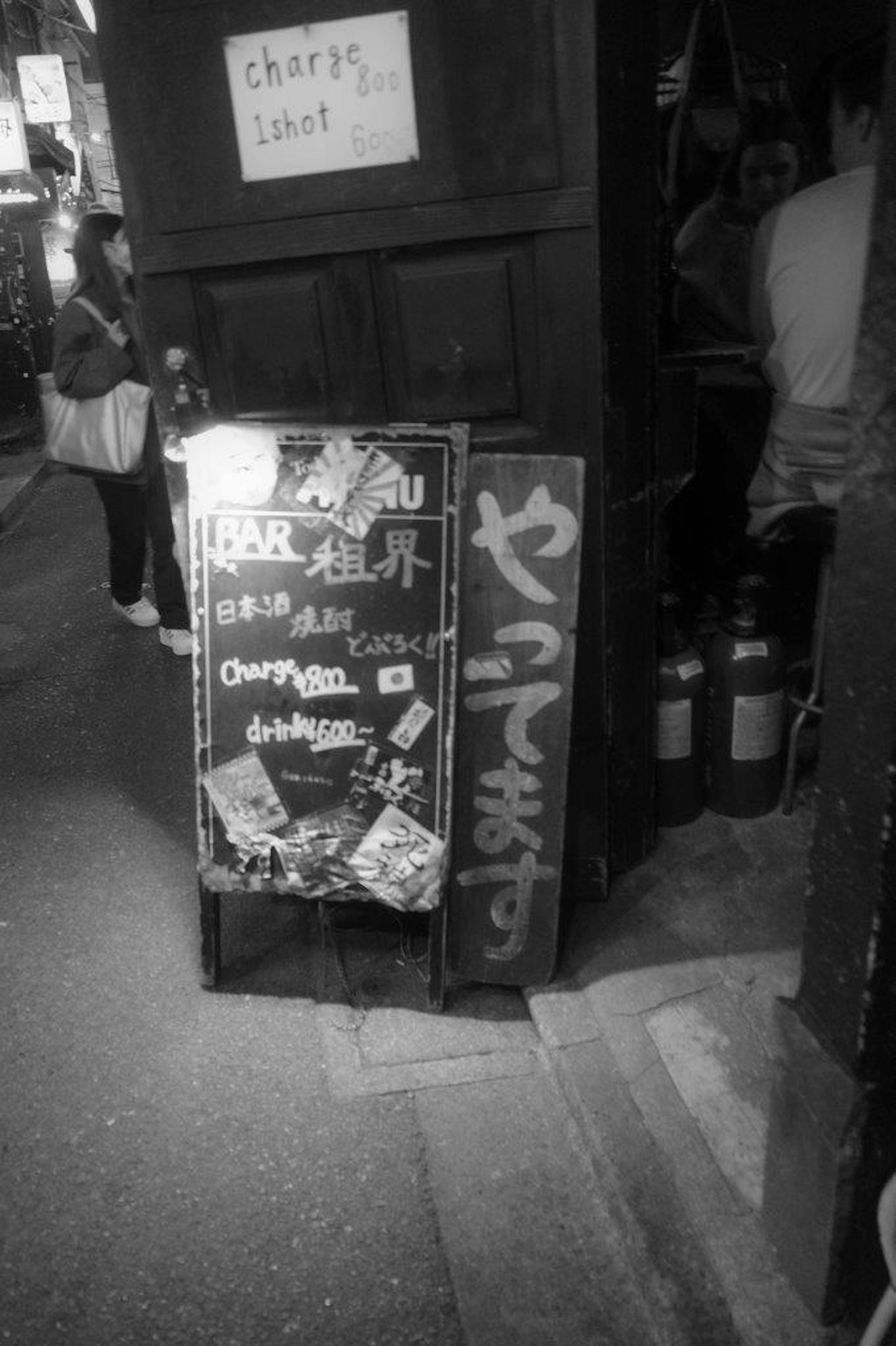 Imagen en blanco y negro de un cartel de restaurante y un menú en un callejón