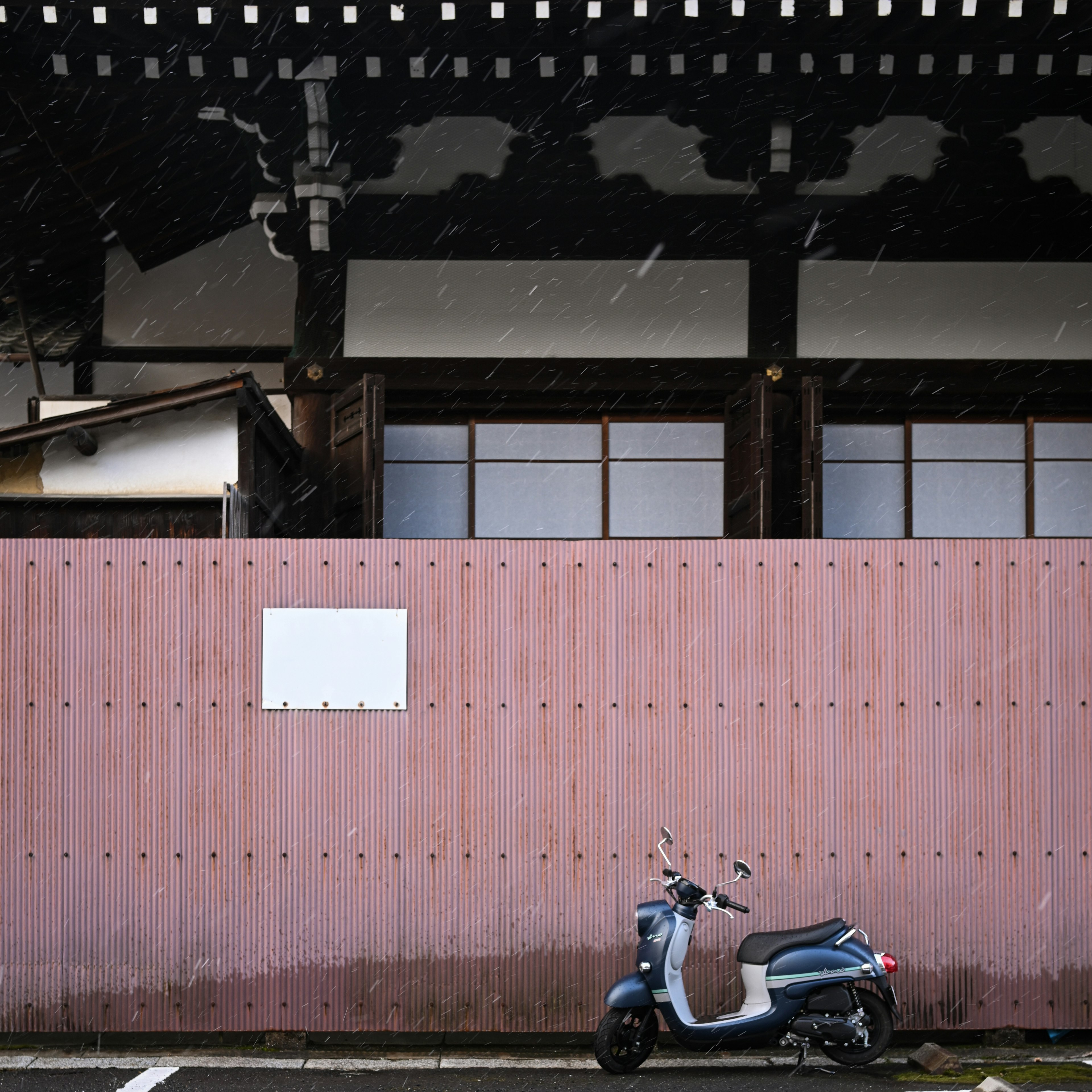 Old Japanese building with a pink wall and a scooter in front