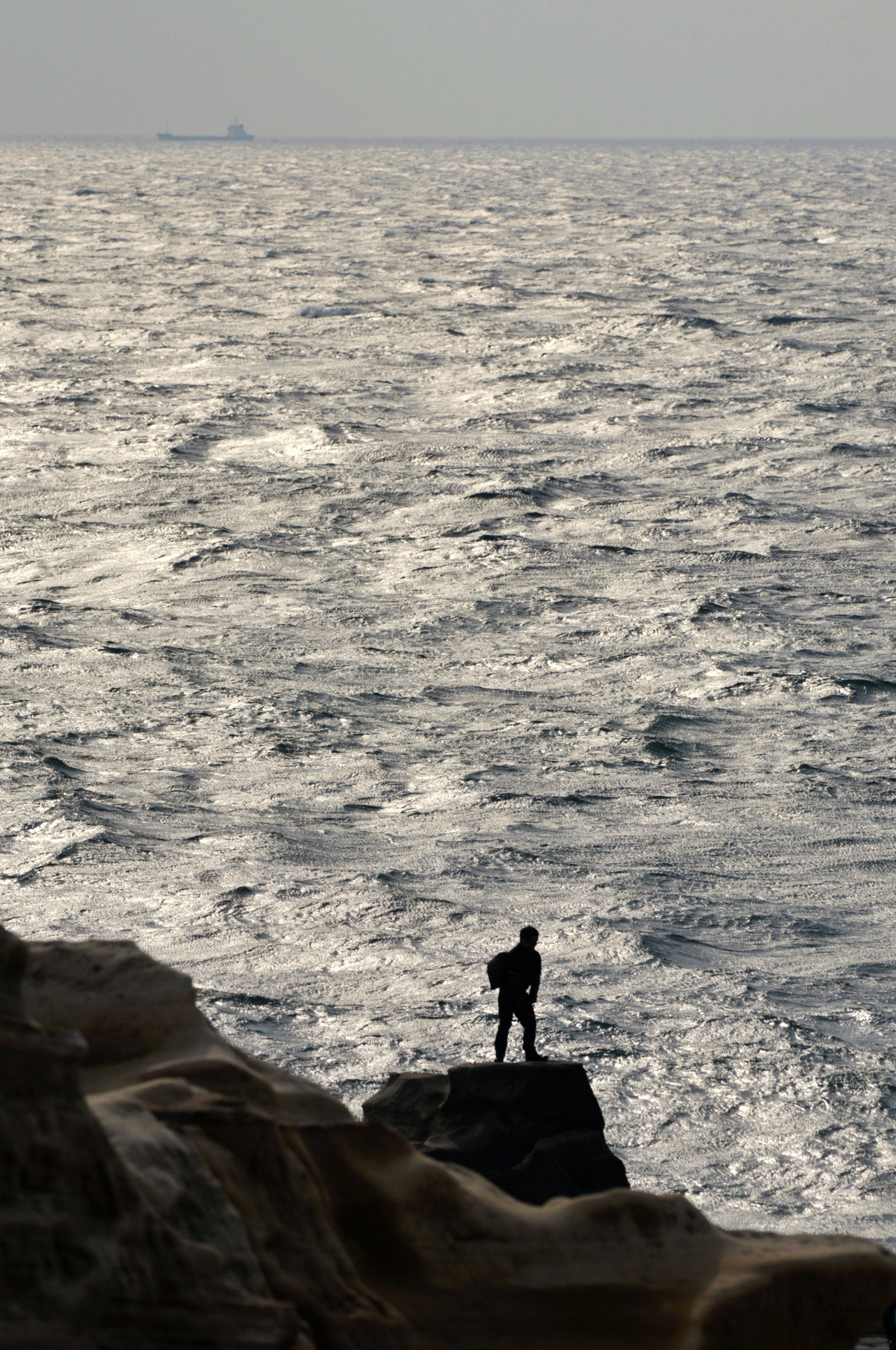 Silhouette of a man standing against the ocean