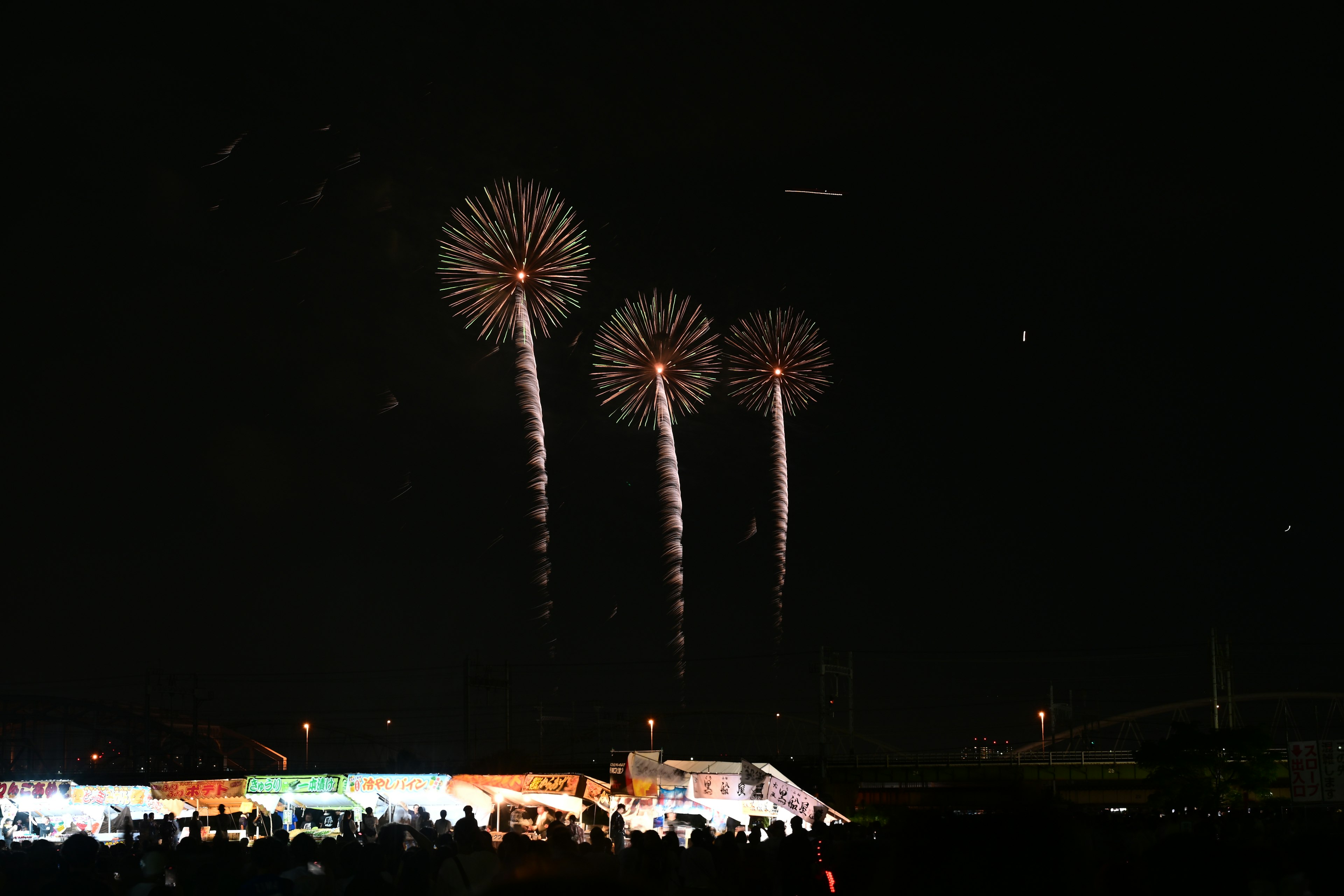 夜空に輝く花火が三つ並んでいる景色