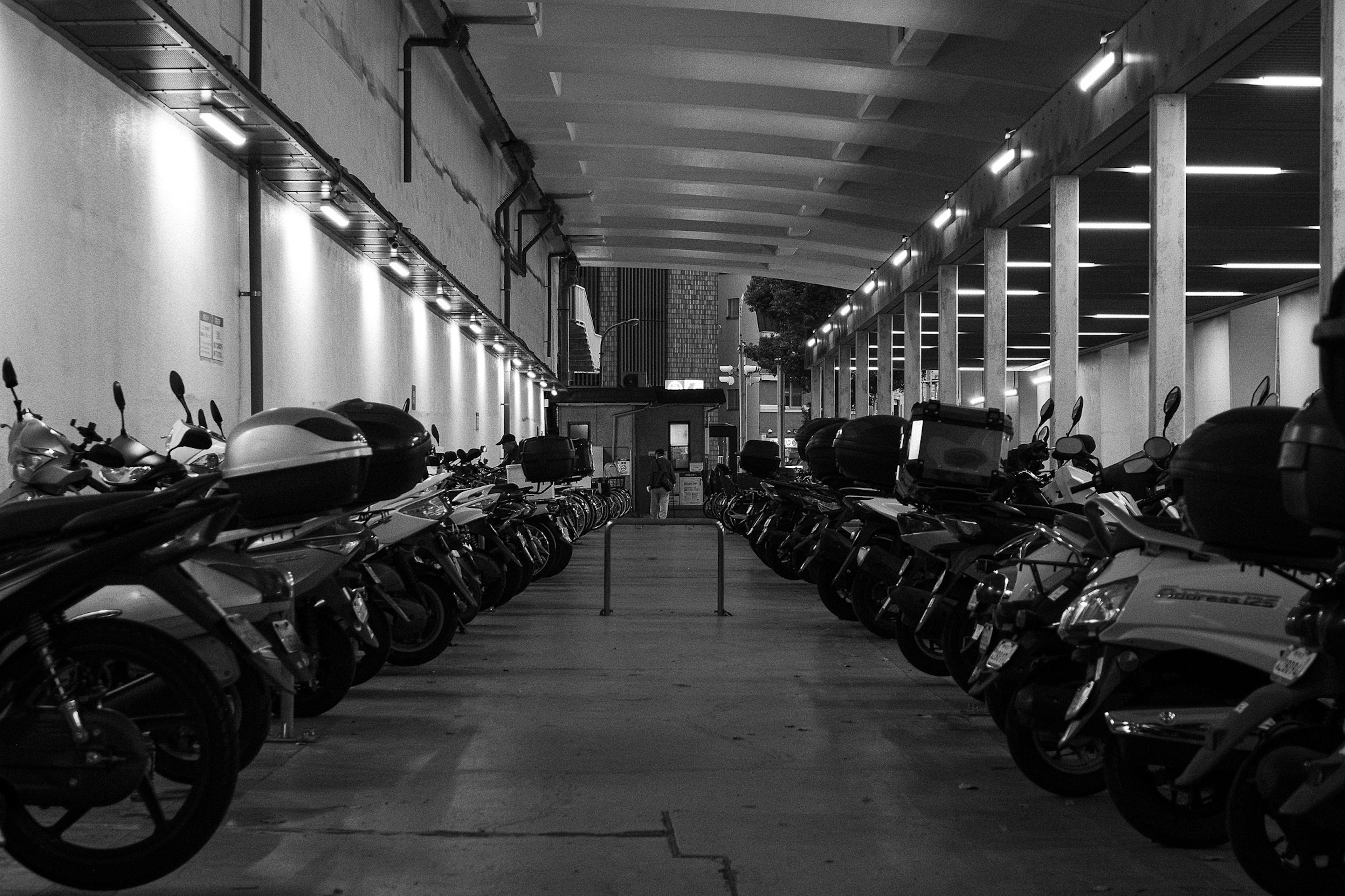 Intérieur d'un grand garage avec des rangées de motos en noir et blanc