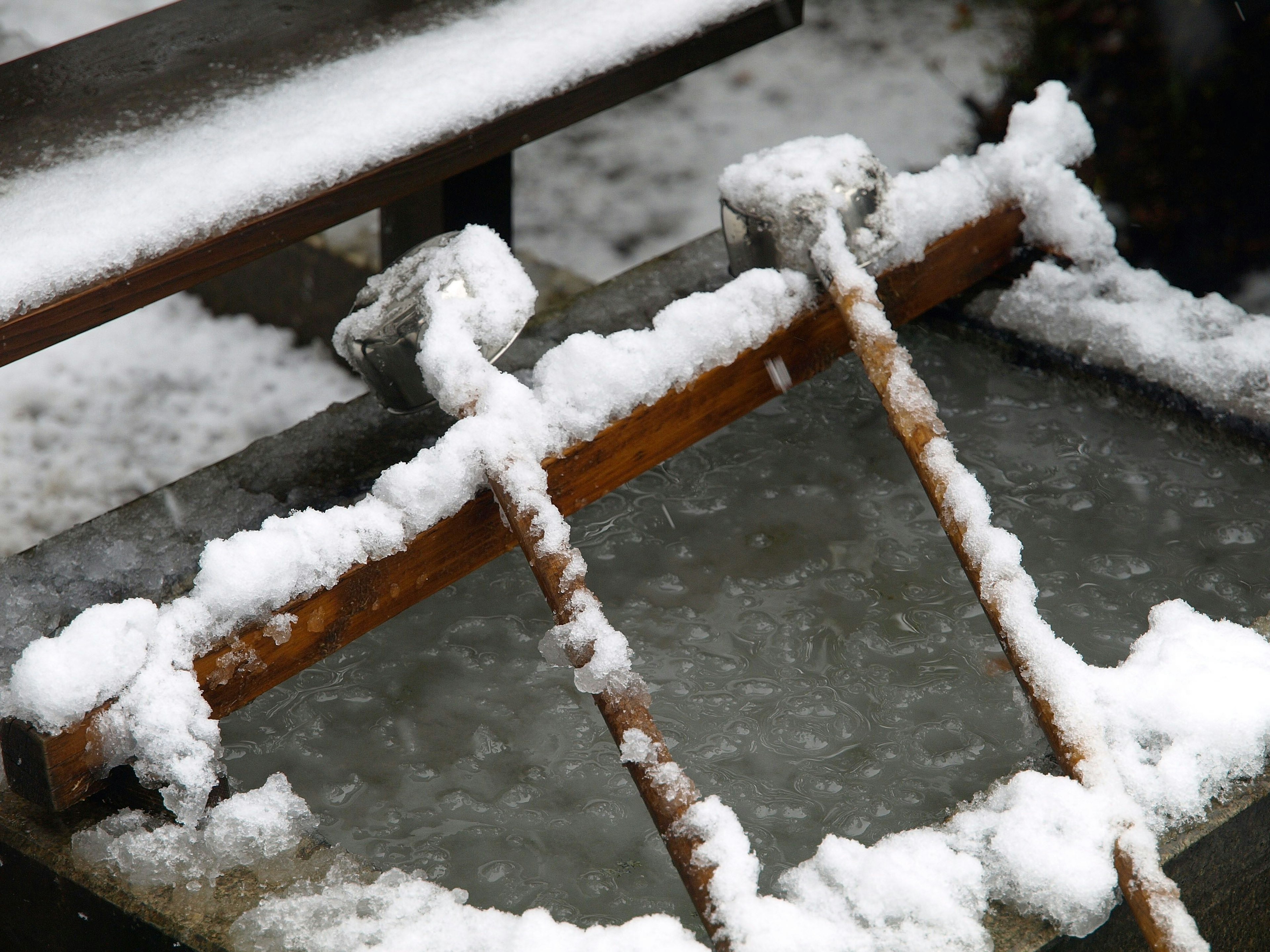 Contenedor lleno de agua cubierto de nieve con palos de madera