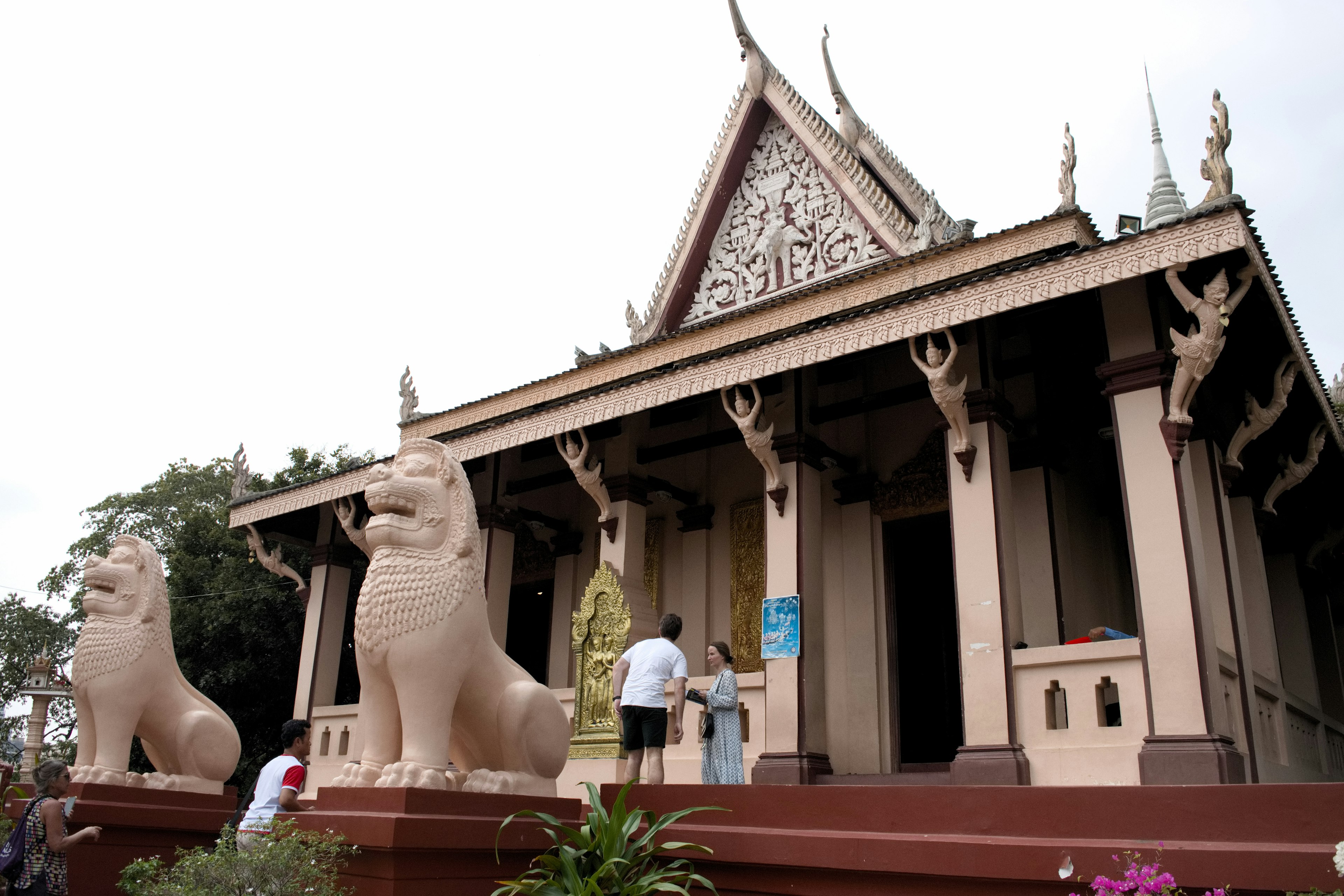 Statues de lions à l'entrée d'un temple avec des visiteurs