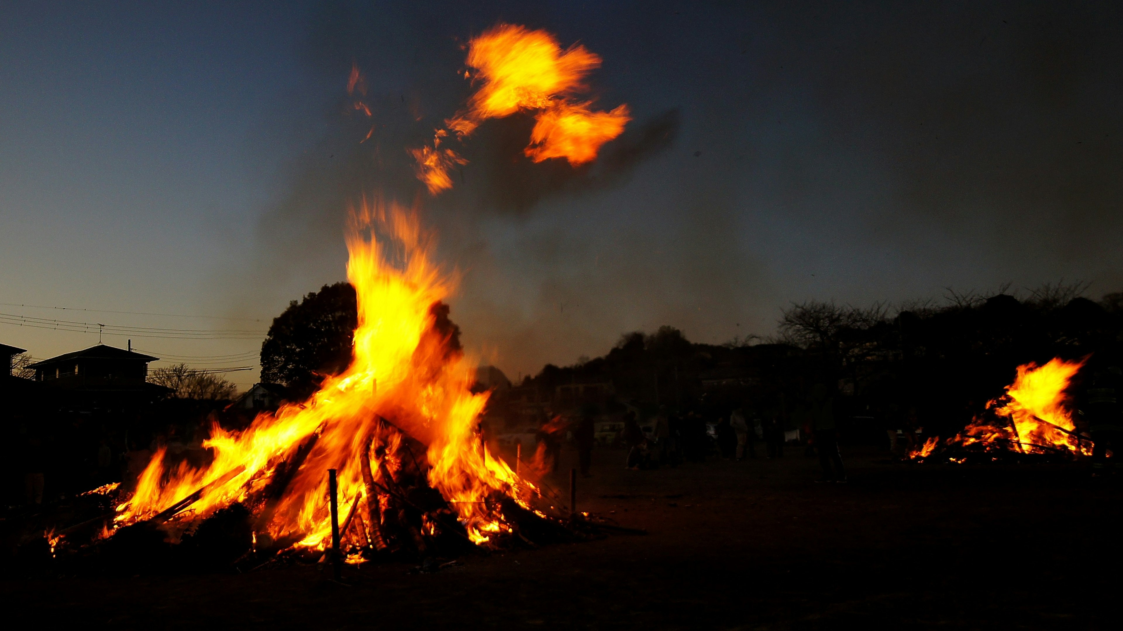 Large bonfire burning at dusk with flames and smoke