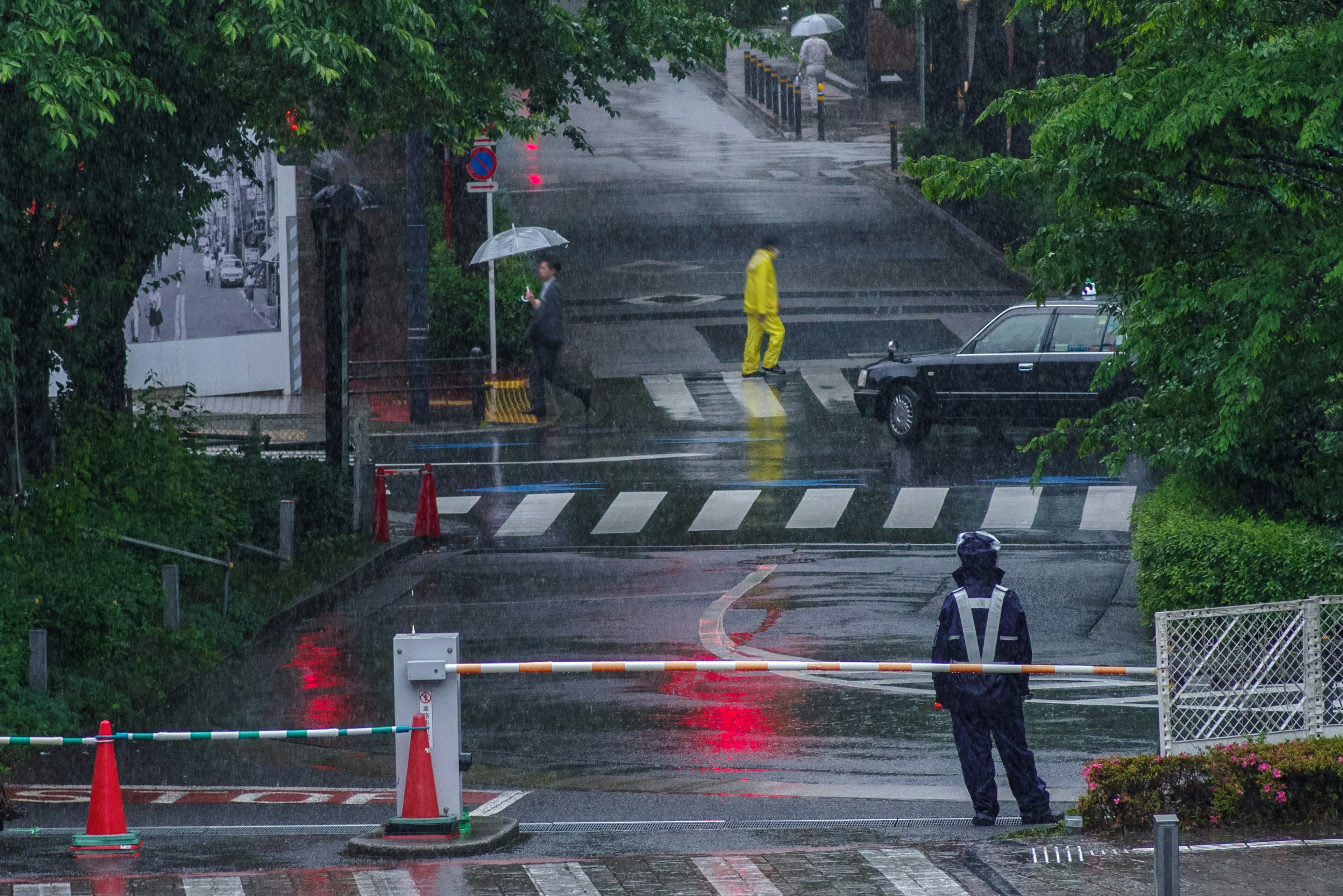 A street scene with a person in a yellow raincoat walking in the rain