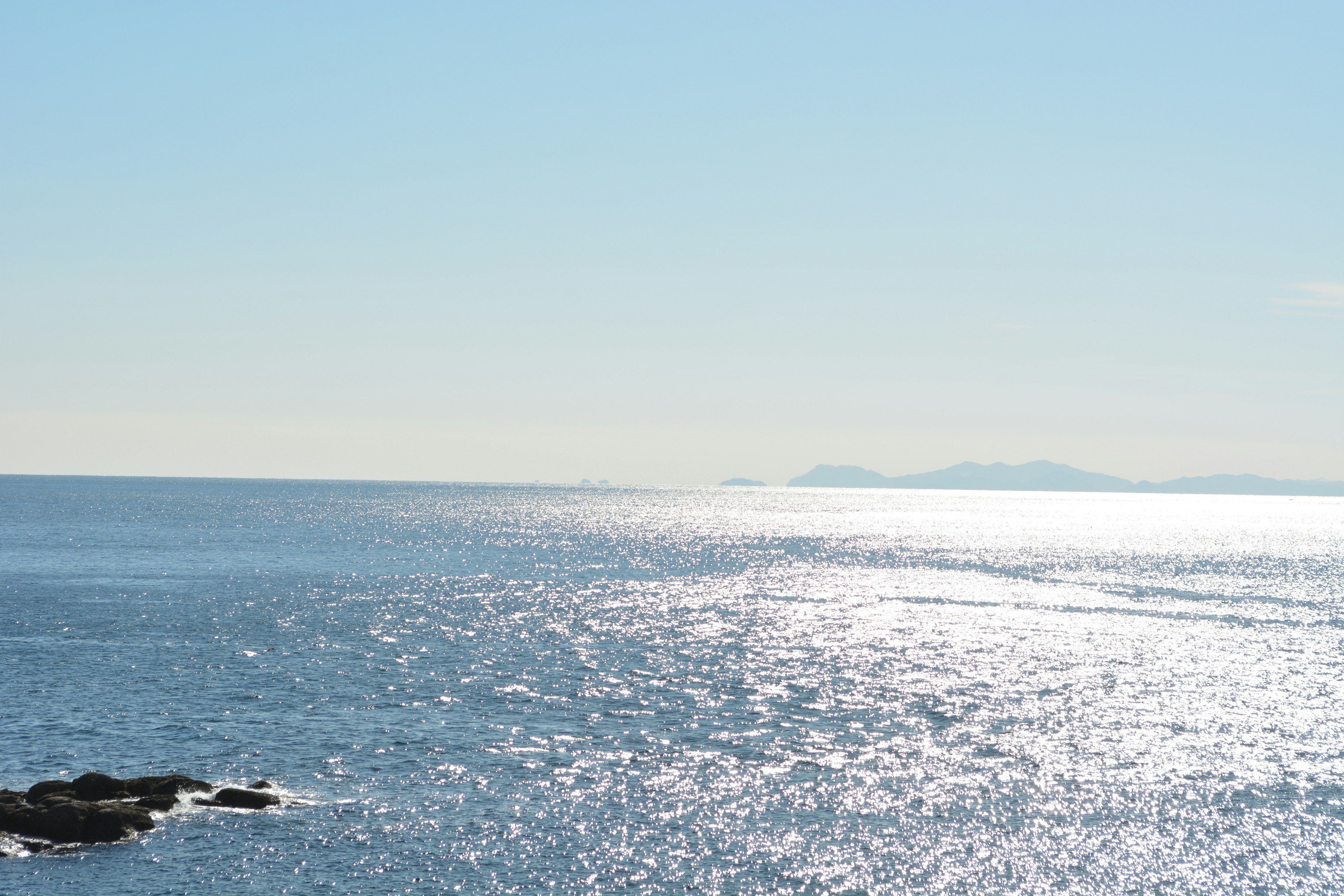 Océan bleu vif sous un ciel dégagé avec des reflets de lumière sur les vagues