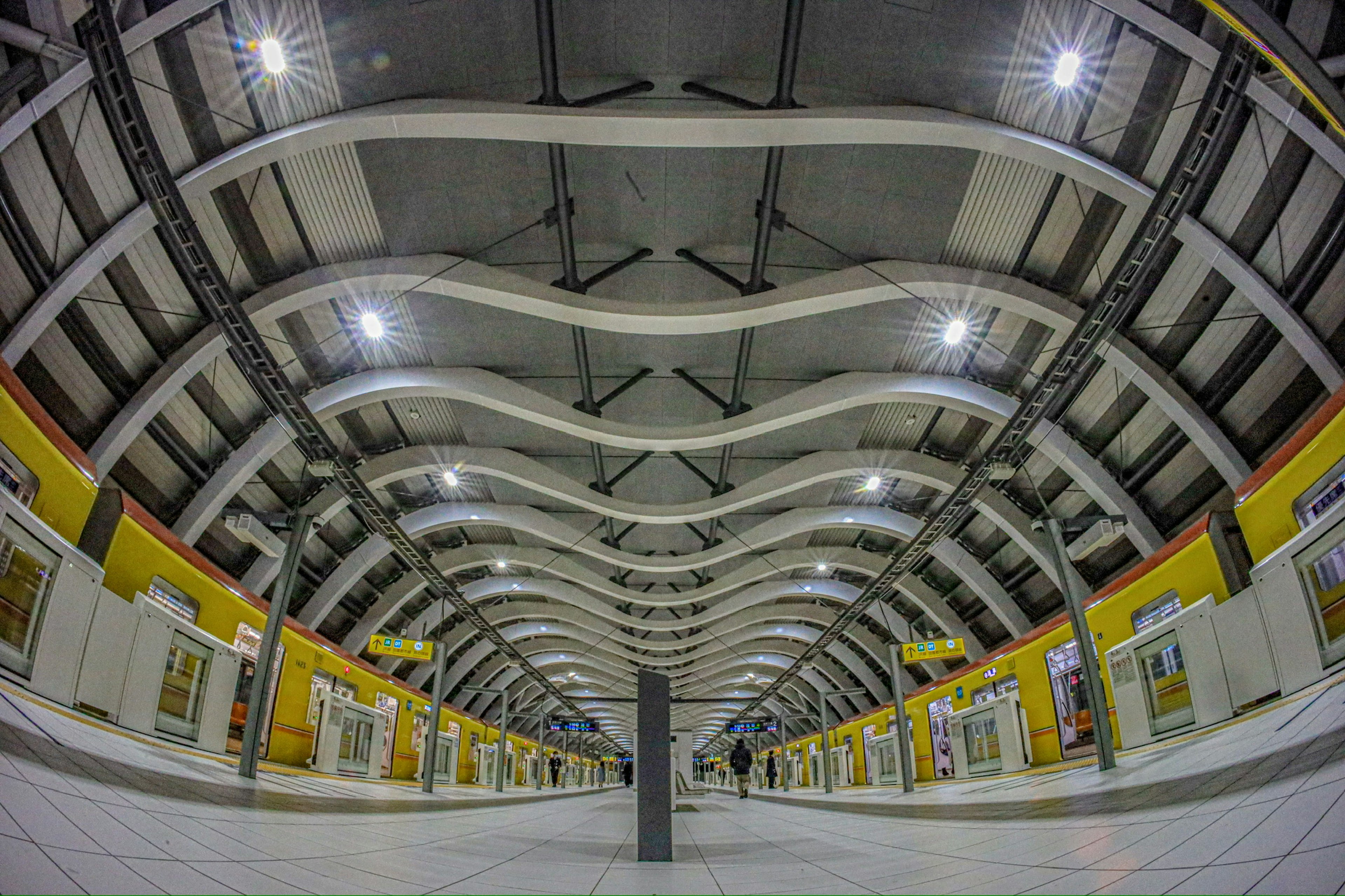 Plataforma de estación amplia con techo ondulado y brillante iluminación