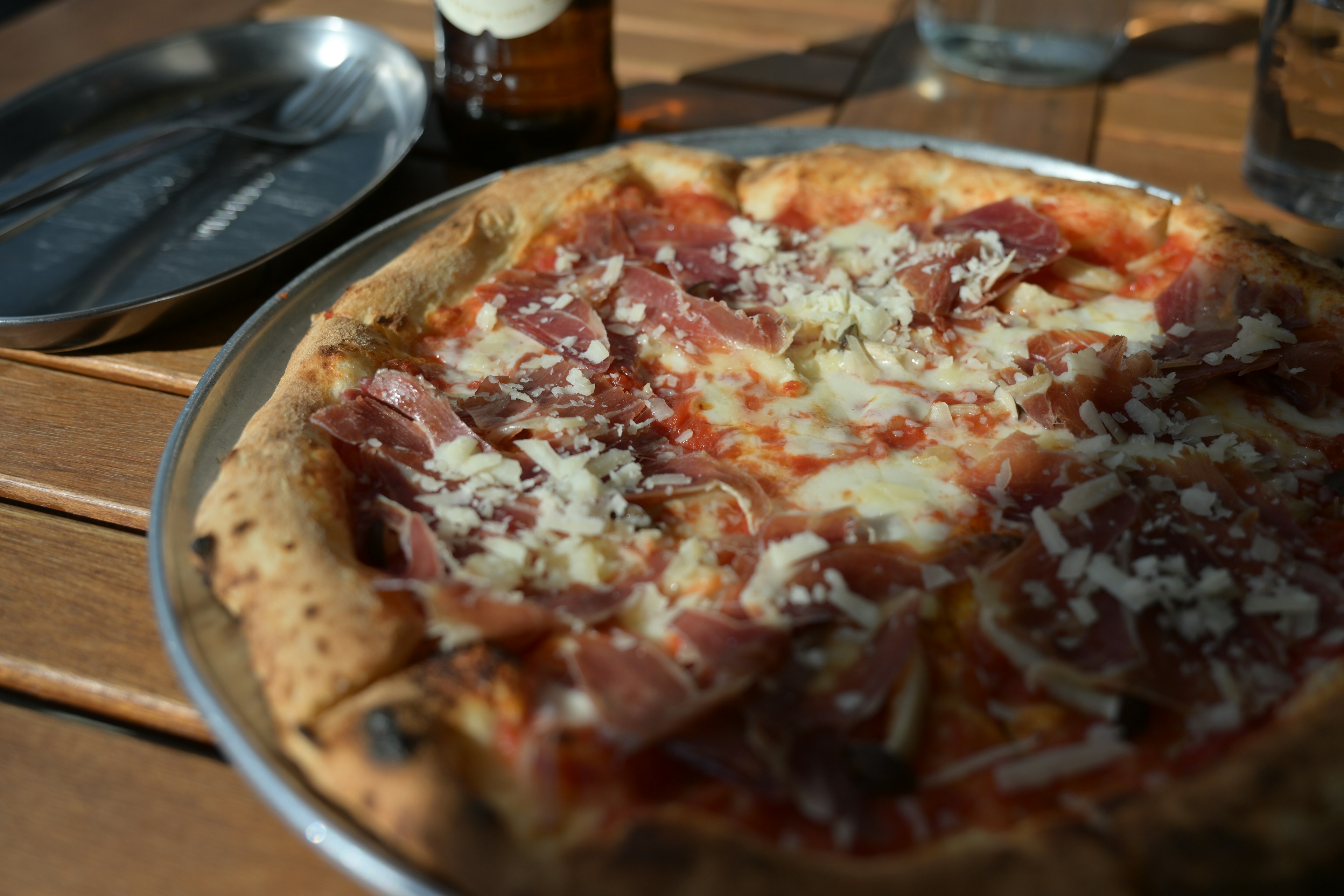 Nahaufnahme einer Pizza mit Schinken und Käse auf einem Holztisch