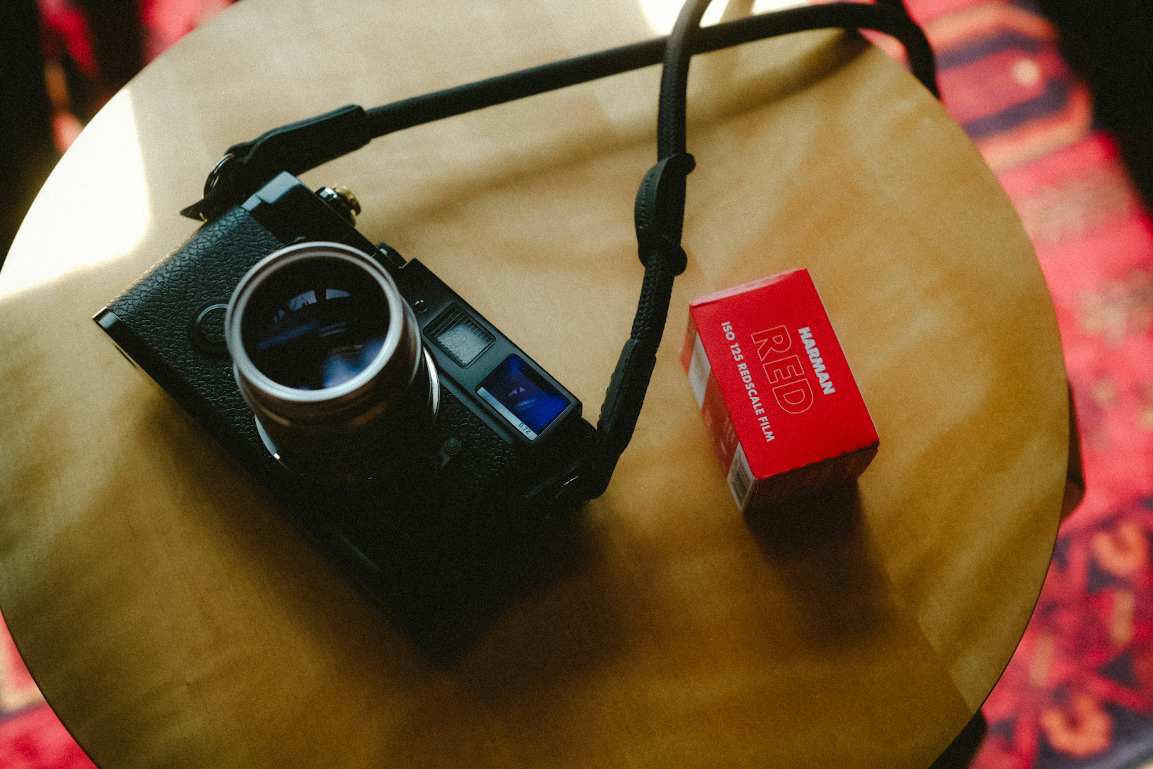 A camera and a red box placed on a wooden table