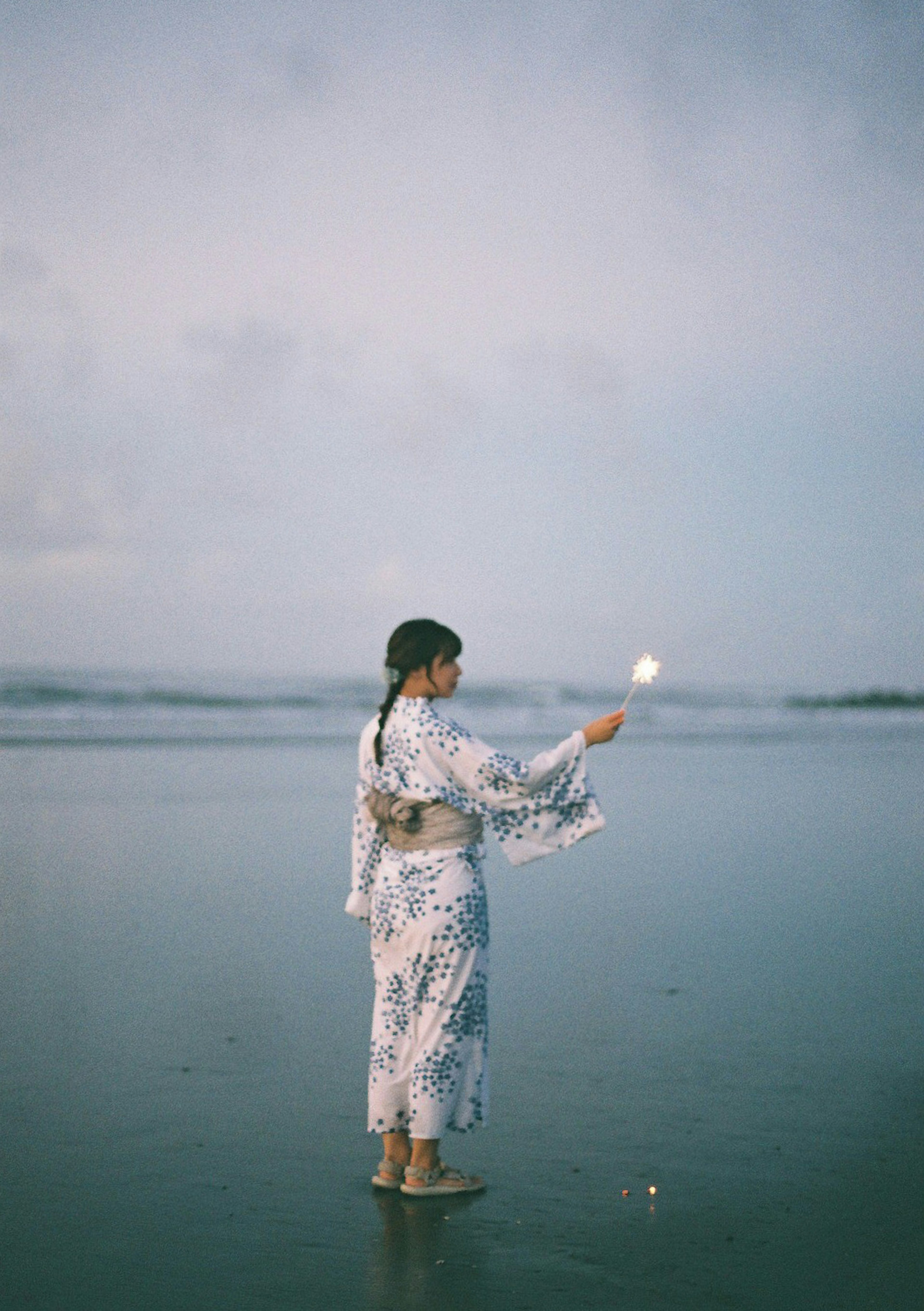 美しい海で着物を着た女性が花火を持って立っている