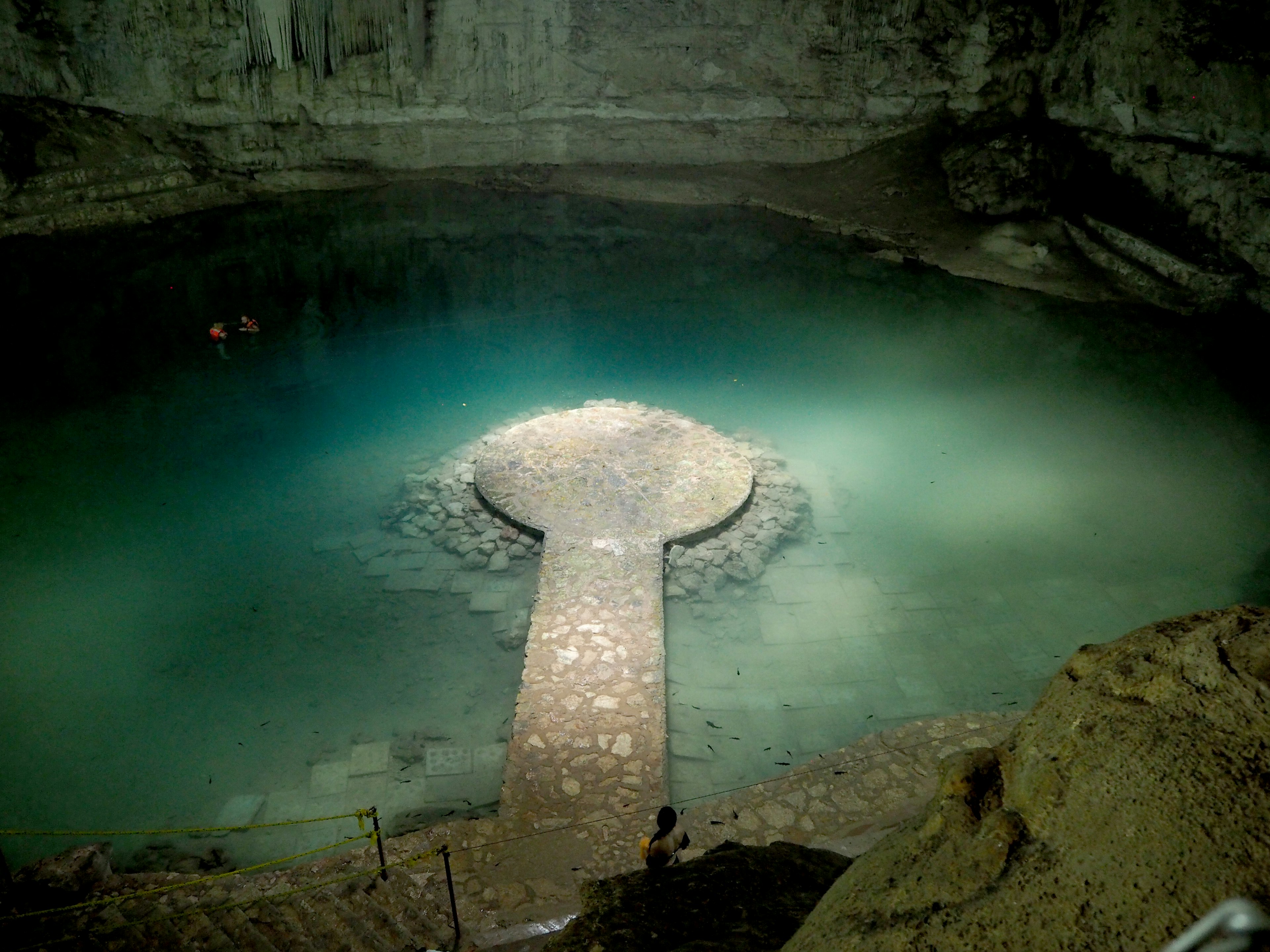 Cueva misteriosa con una pequeña isla y un camino de piedra sobre el agua