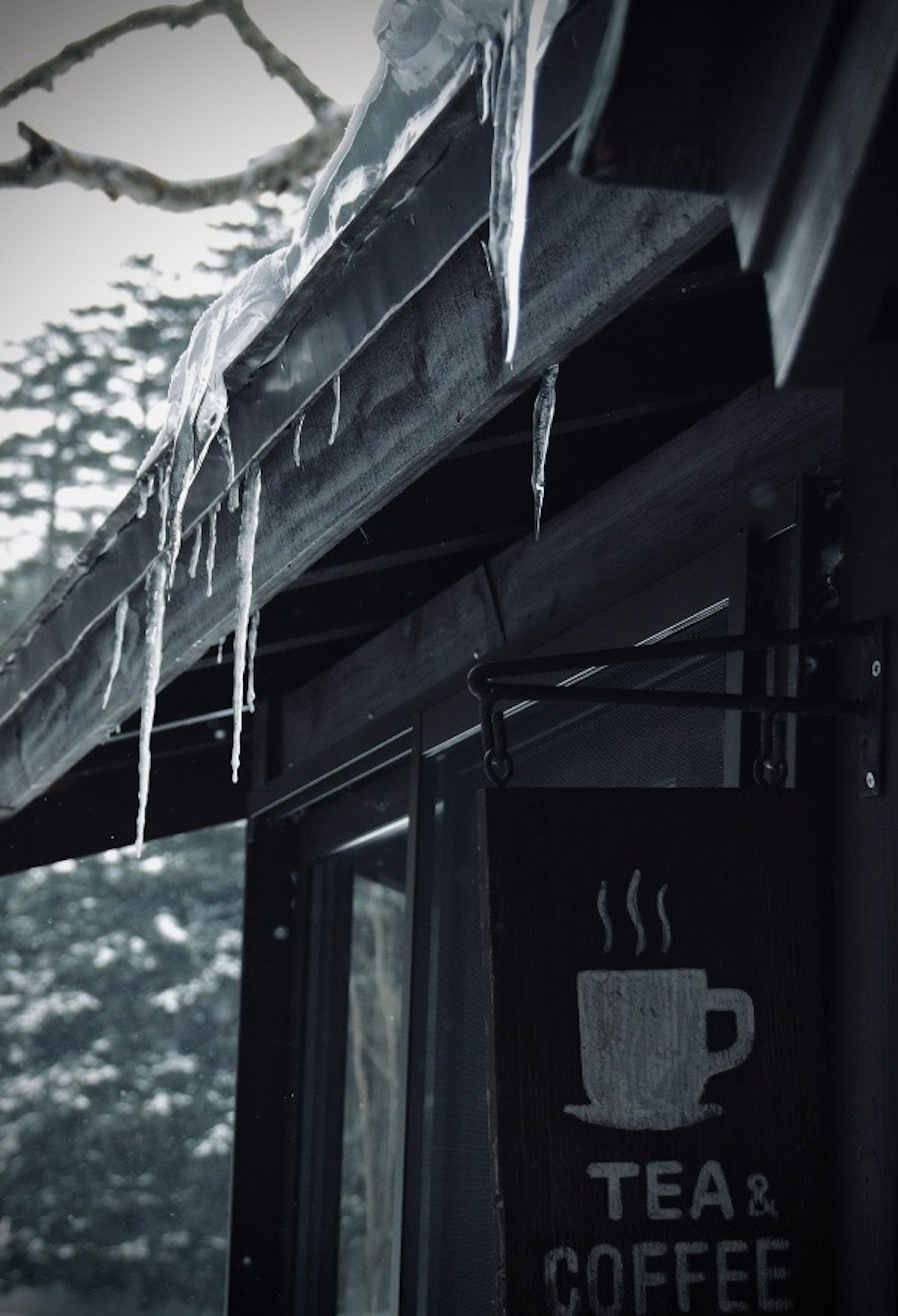 冰柱懸掛在雪景中的茶和咖啡店的屋頂上