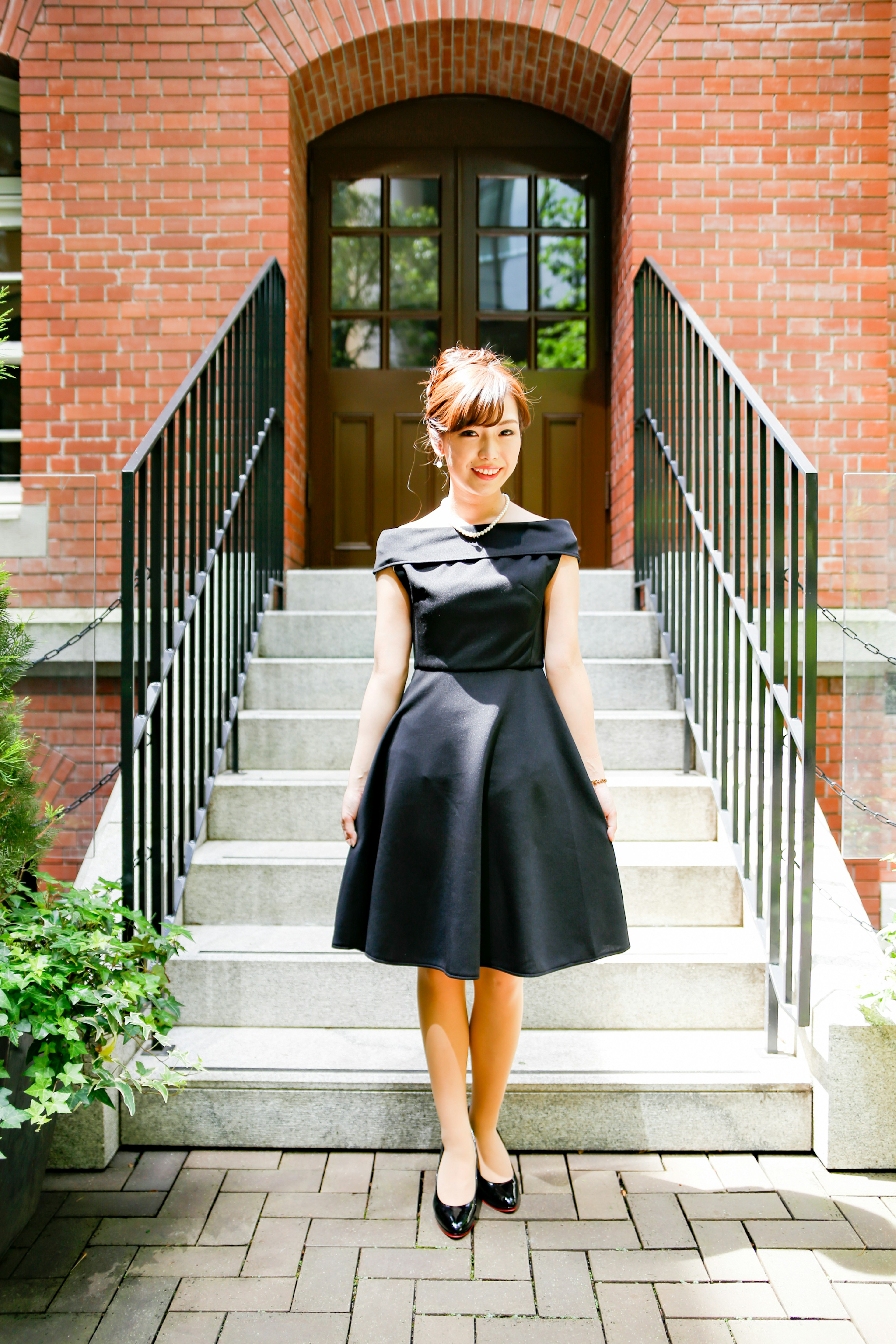 Eine Frau in einem schwarzen Kleid steht vor einer Treppe