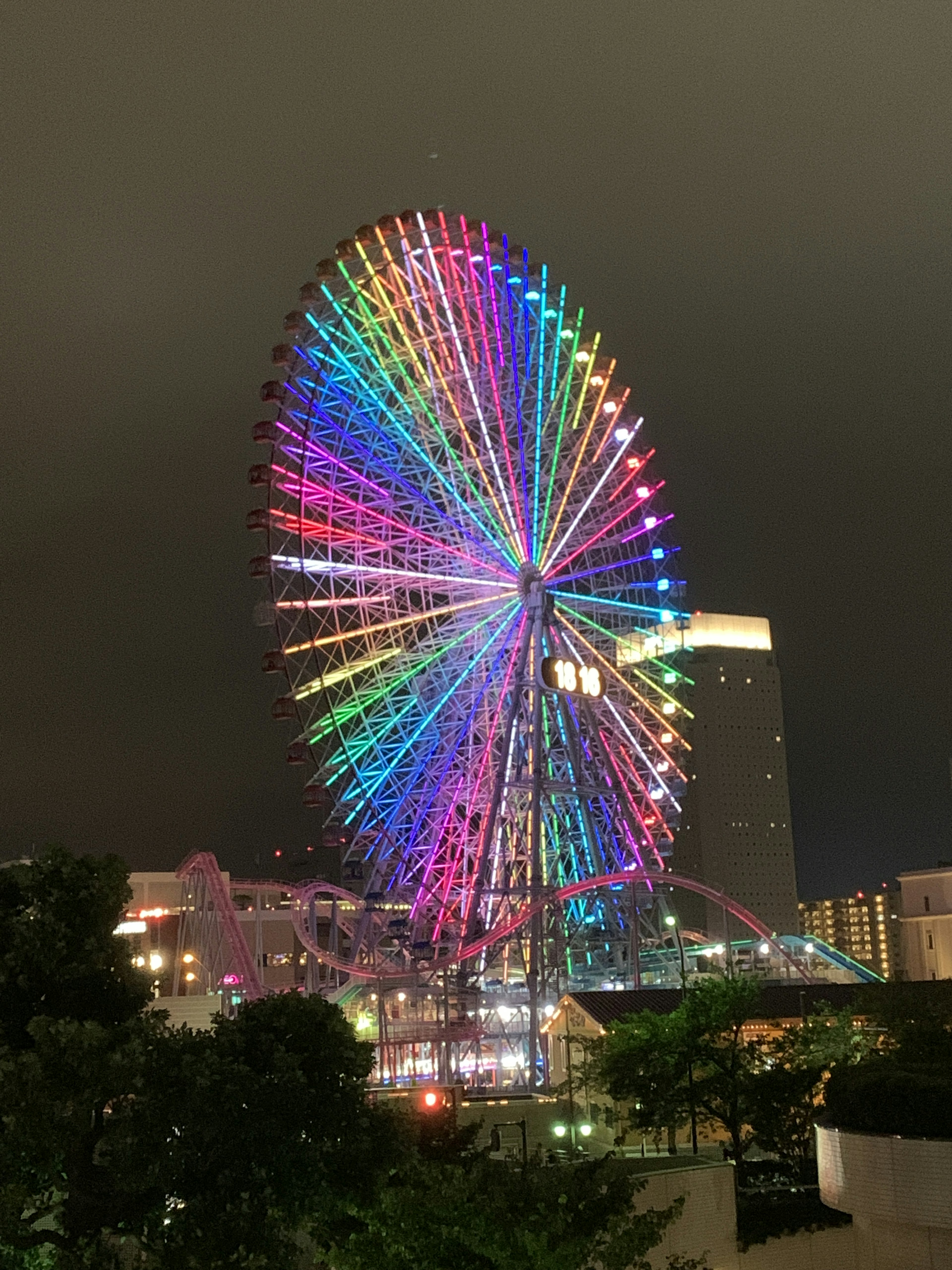 Bunte Riesenrad bei Nacht beleuchtet mit Stadtansicht