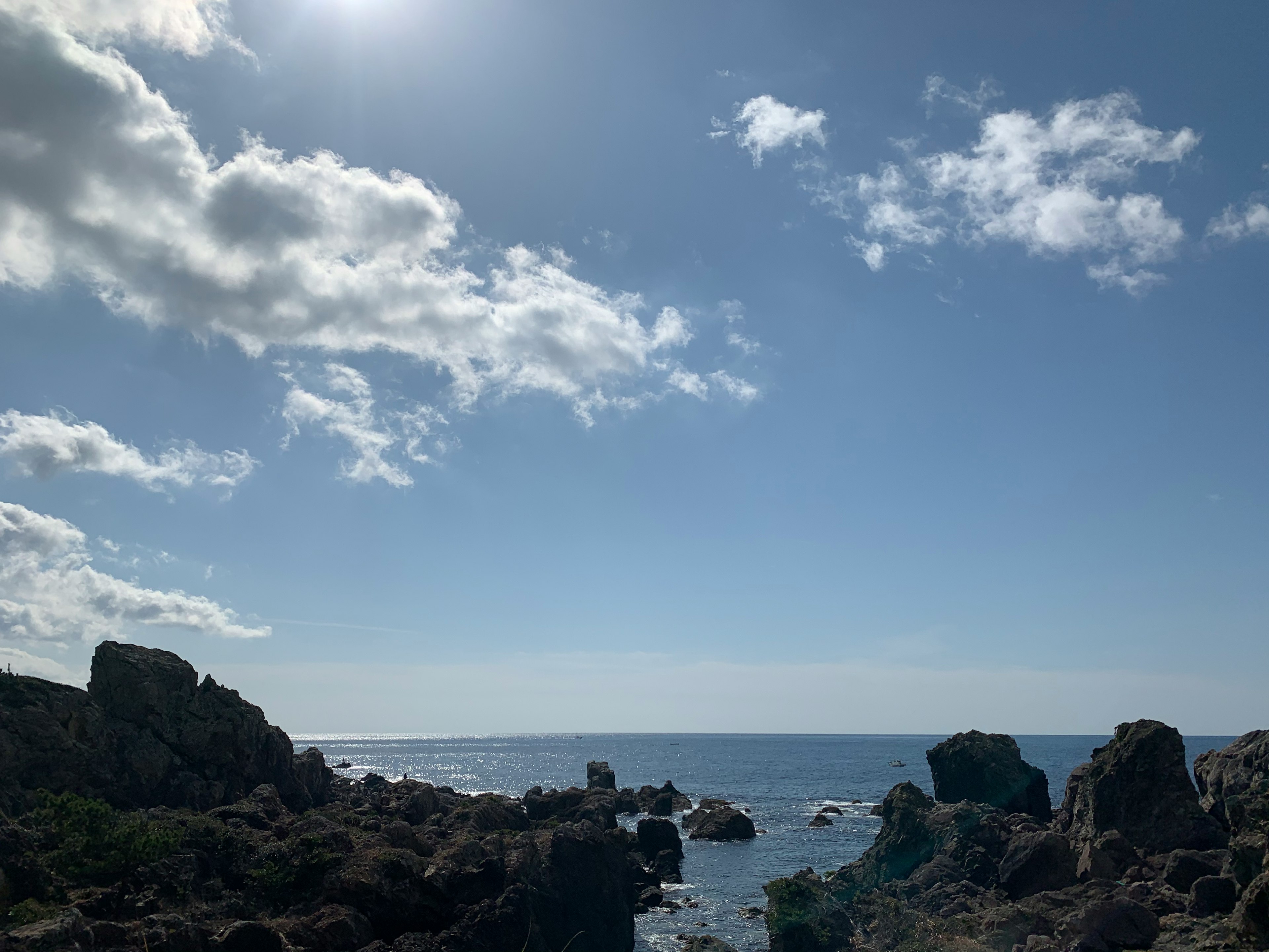 Vista costiera con rocce e cielo blu con nuvole bianche