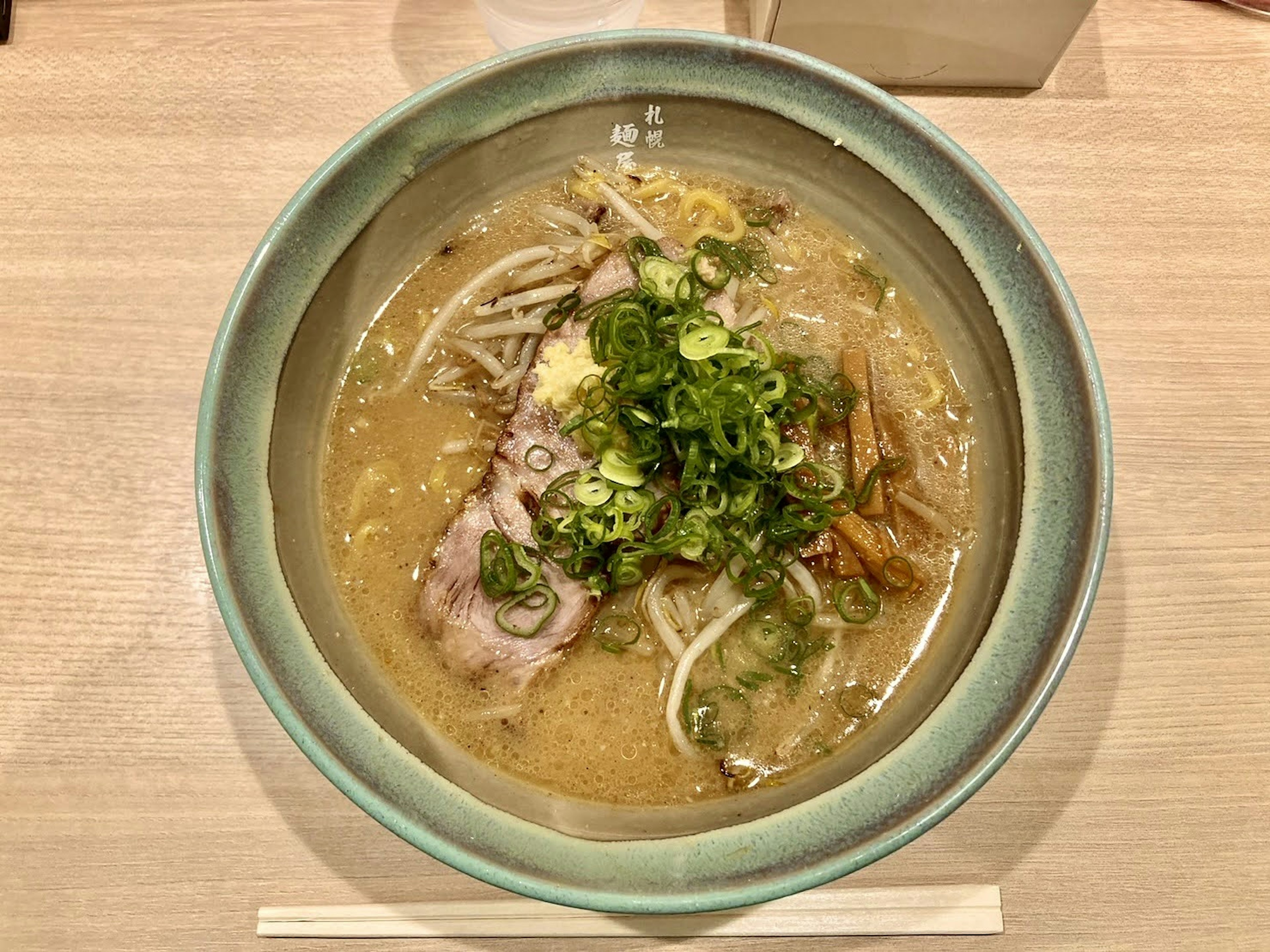 Delicious ramen bowl with rich broth topped with green onions and slices of meat