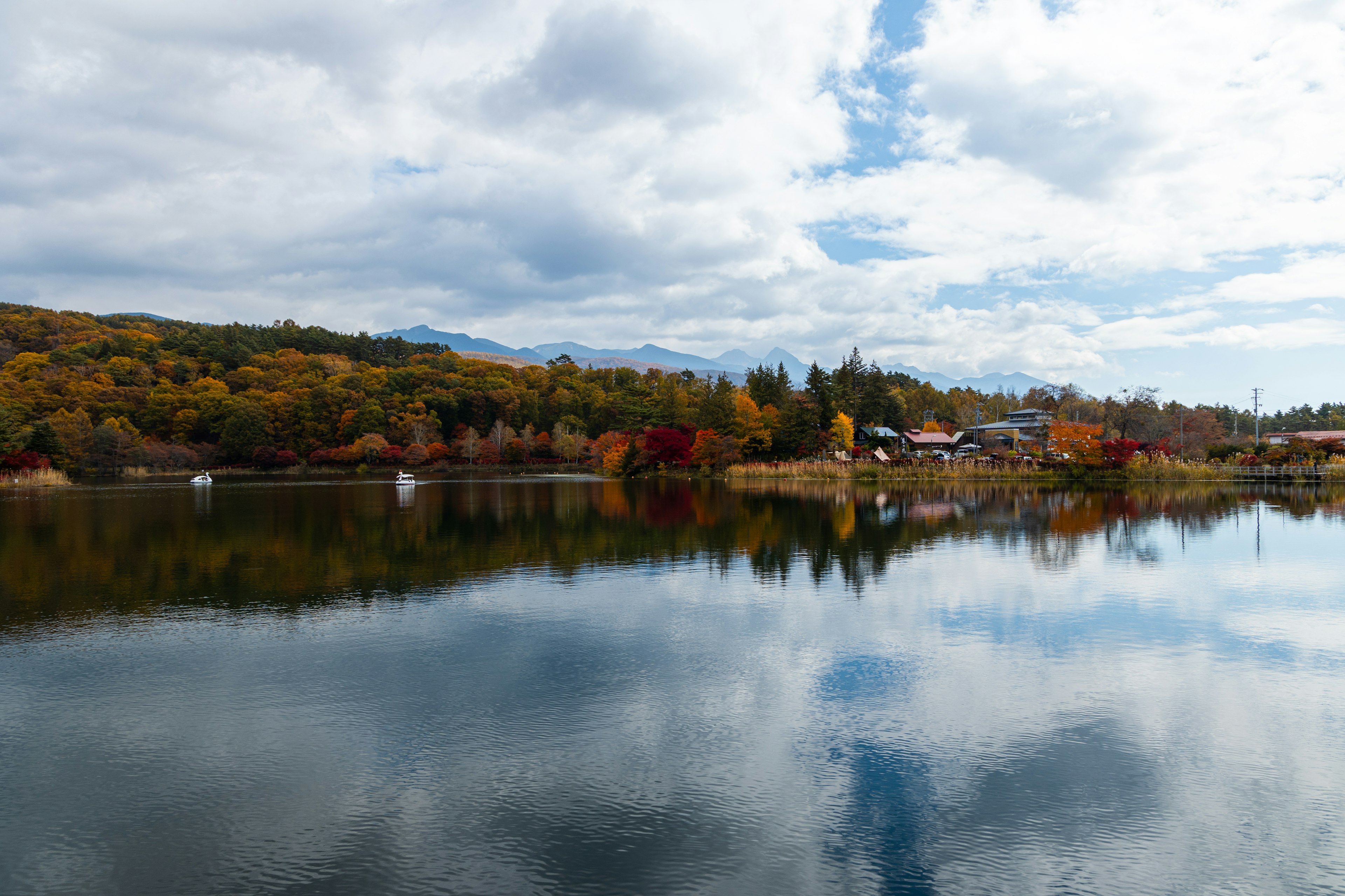 Lac pittoresque reflétant le feuillage automnal coloré et le ciel nuageux