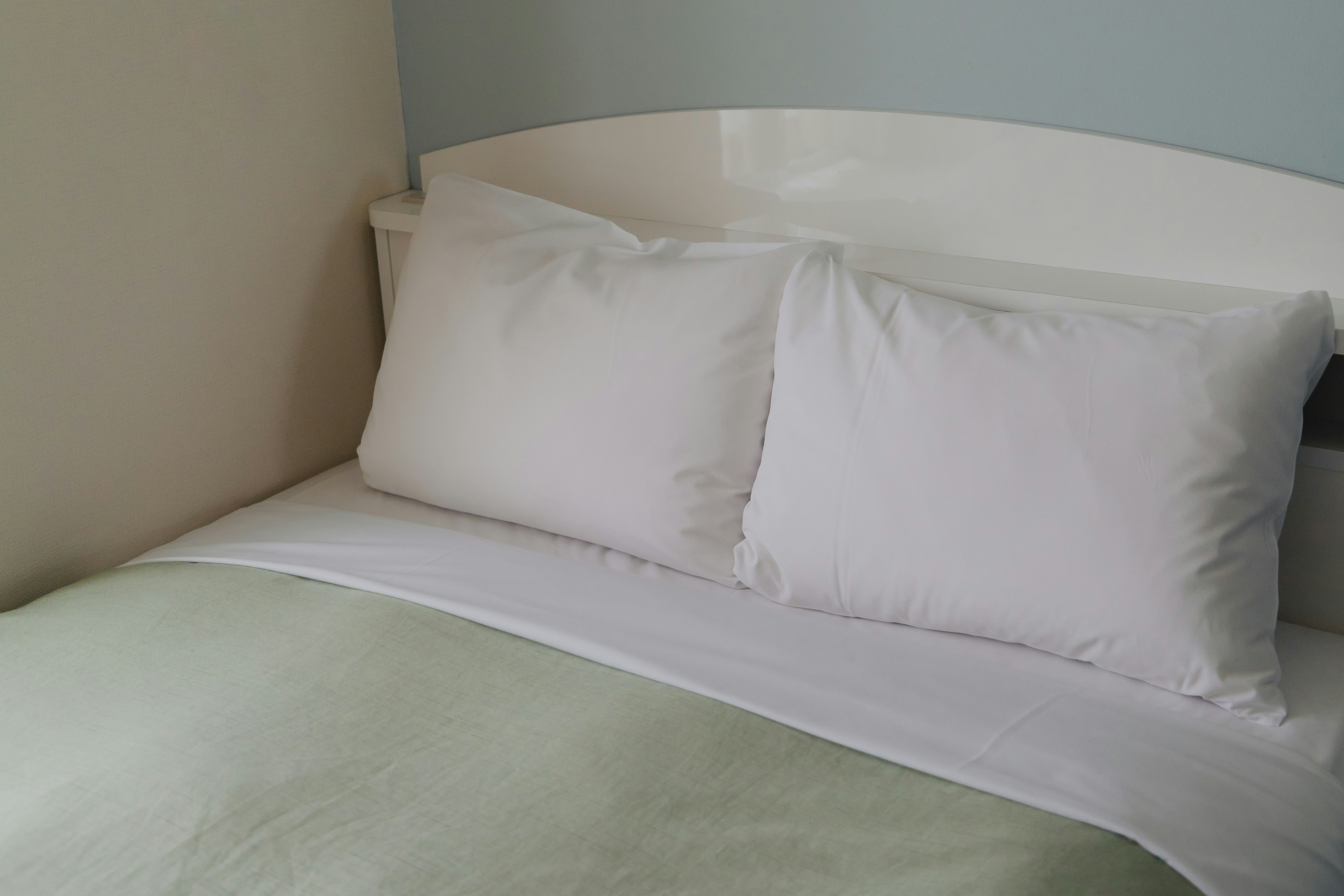 Close-up of a bed with white pillows and a green comforter