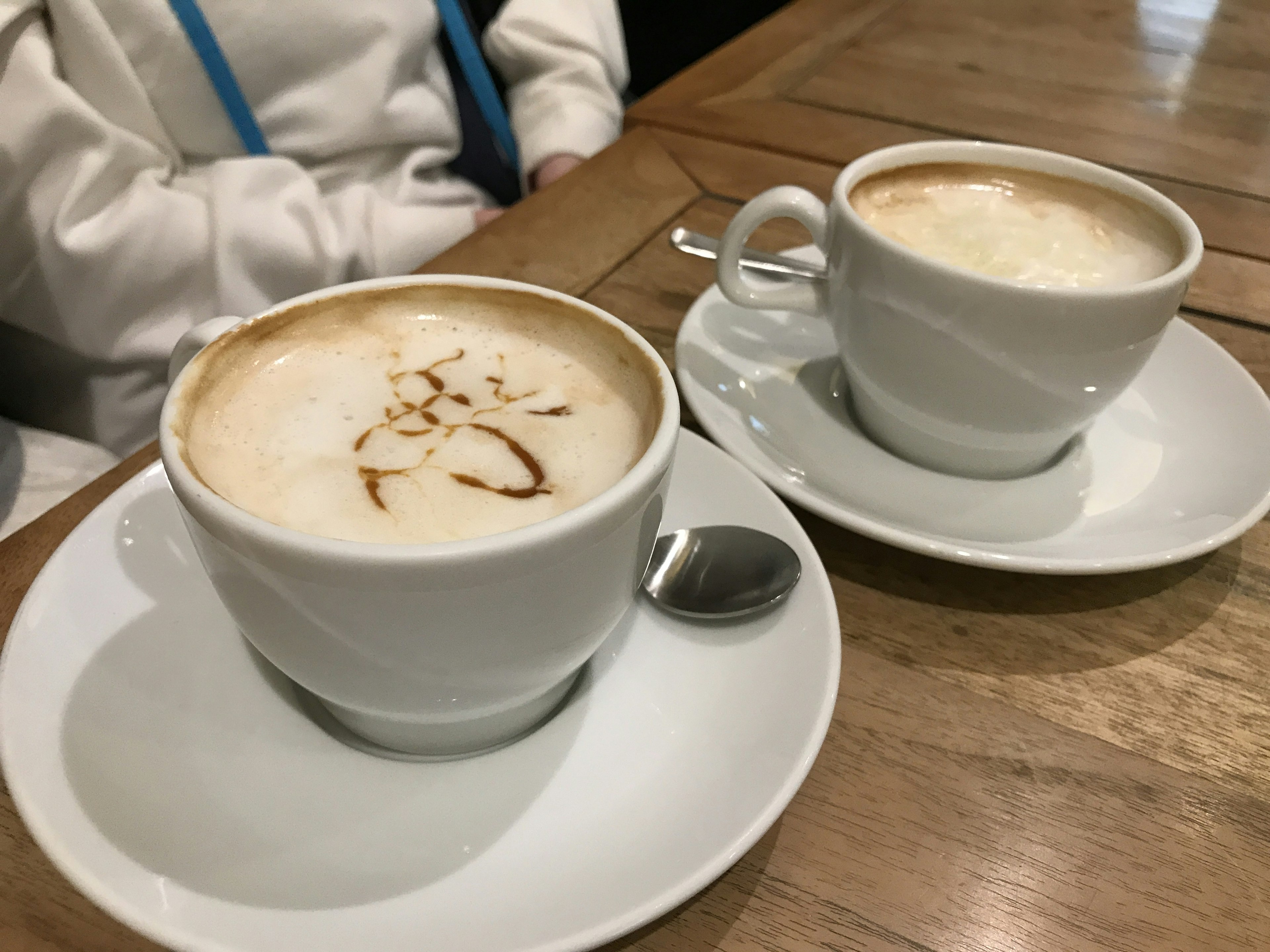 Two cappuccinos in white cups on a wooden table