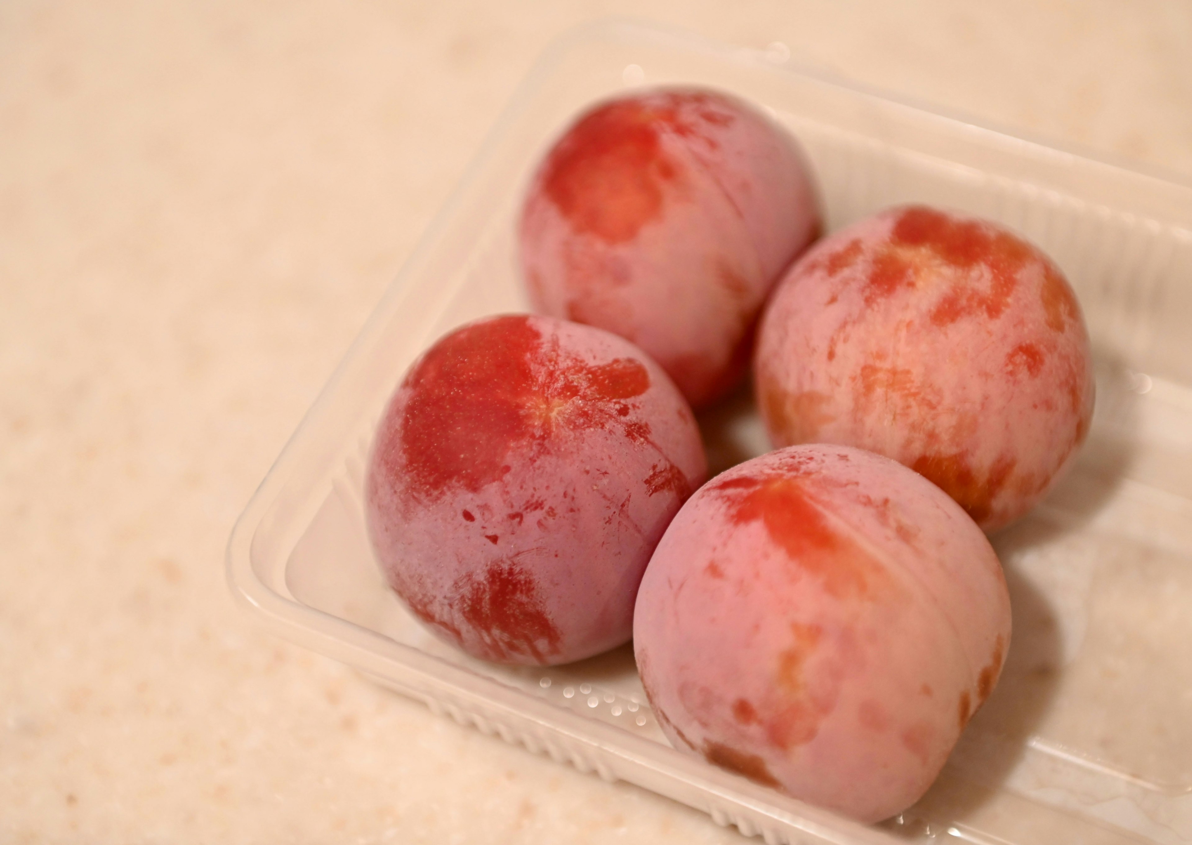 Four peaches in a clear plastic container