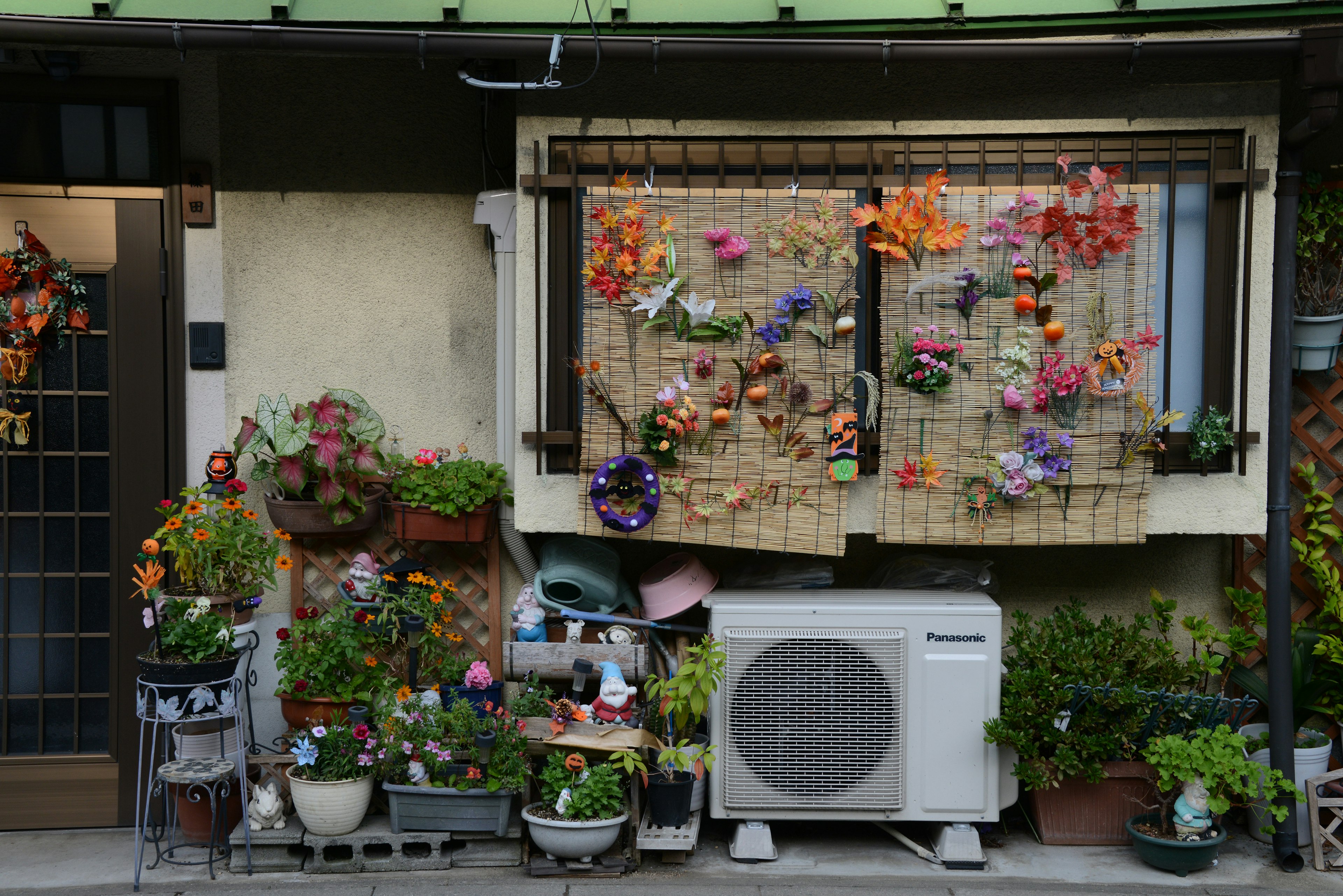 Außenansicht eines Hauses, geschmückt mit bunten Blumen und zahlreichen Blumentöpfen