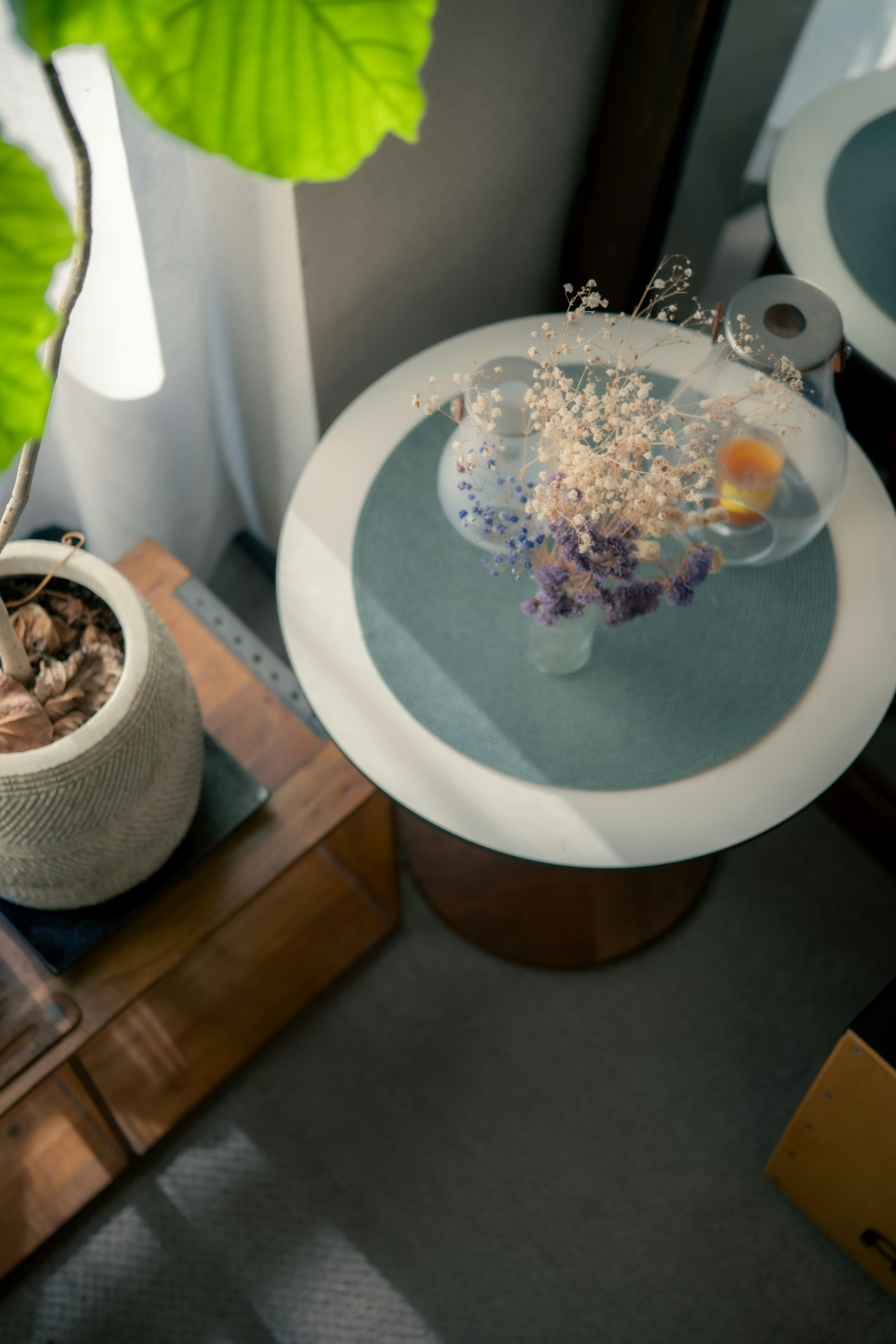 Round white table with a glass vase filled with flowers and decorative elements