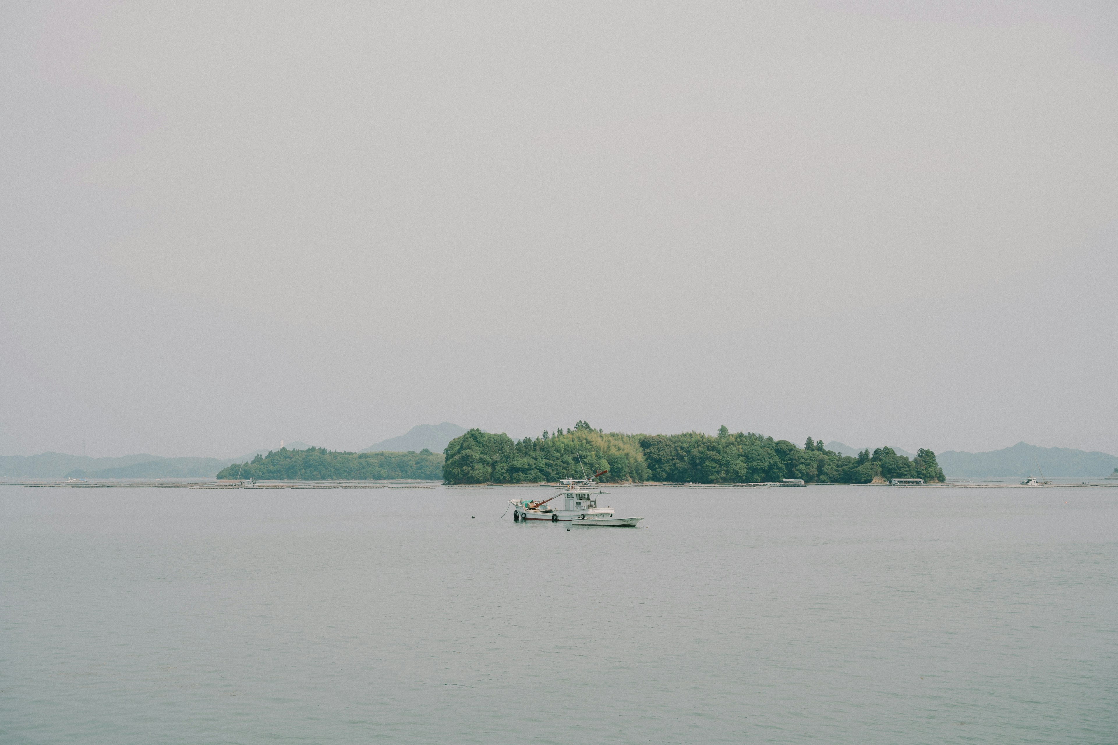 เกาะเล็กๆ ที่มีพืชพรรณเขียวชอุ่มในทะเลสาบสงบพร้อมเรือ