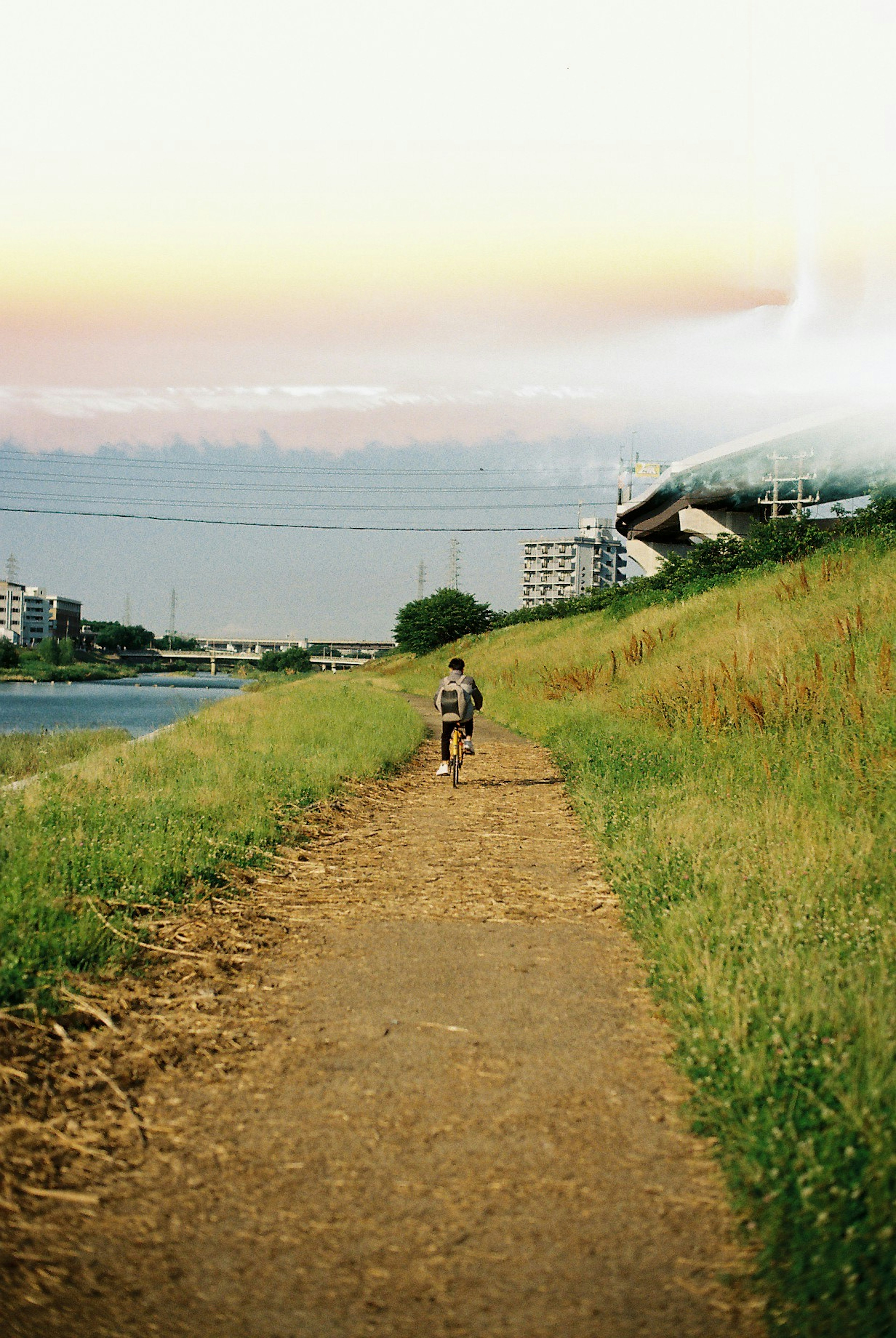 A person walking along a grassy path beside a river