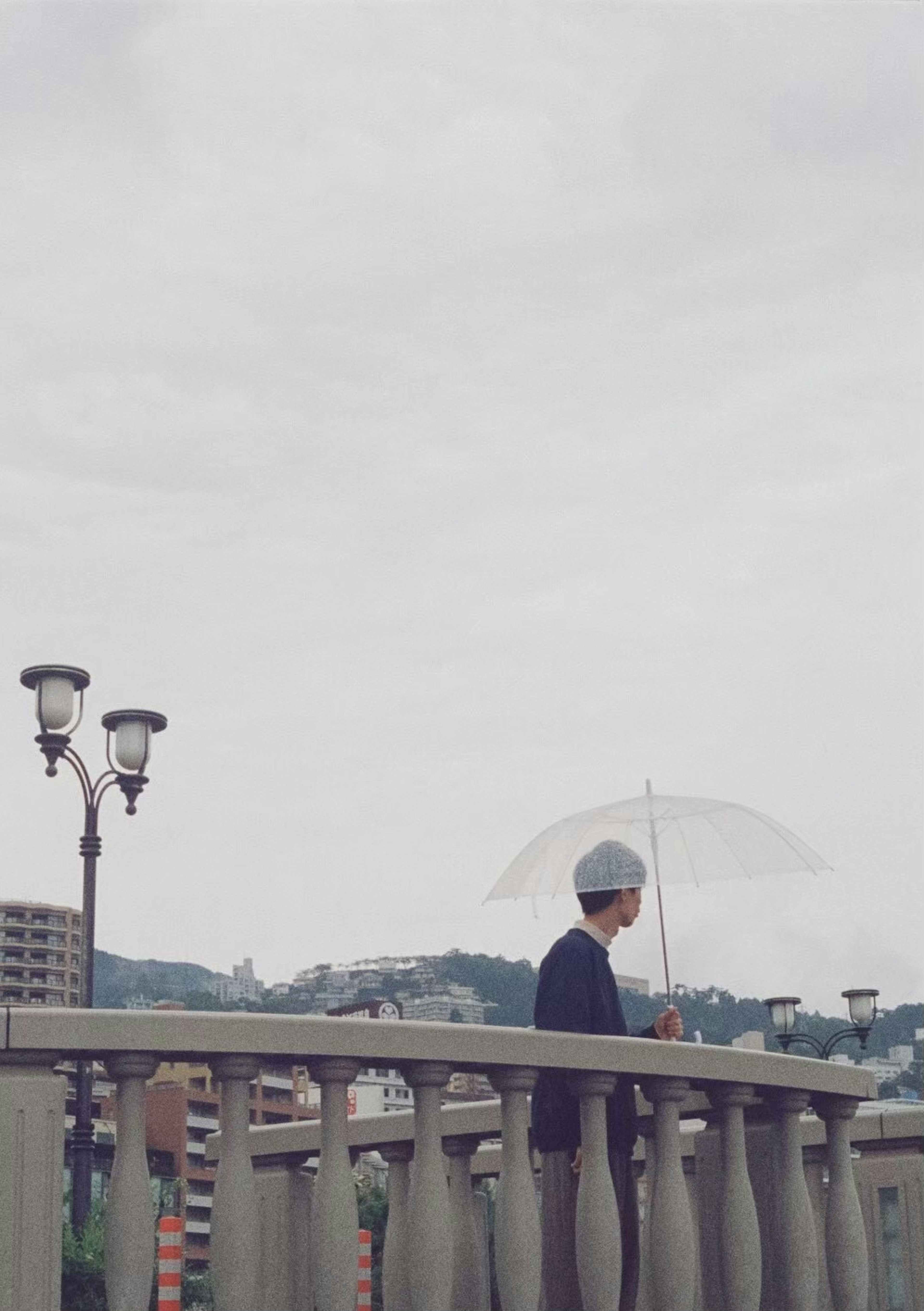 手持雨傘的人站在橋上