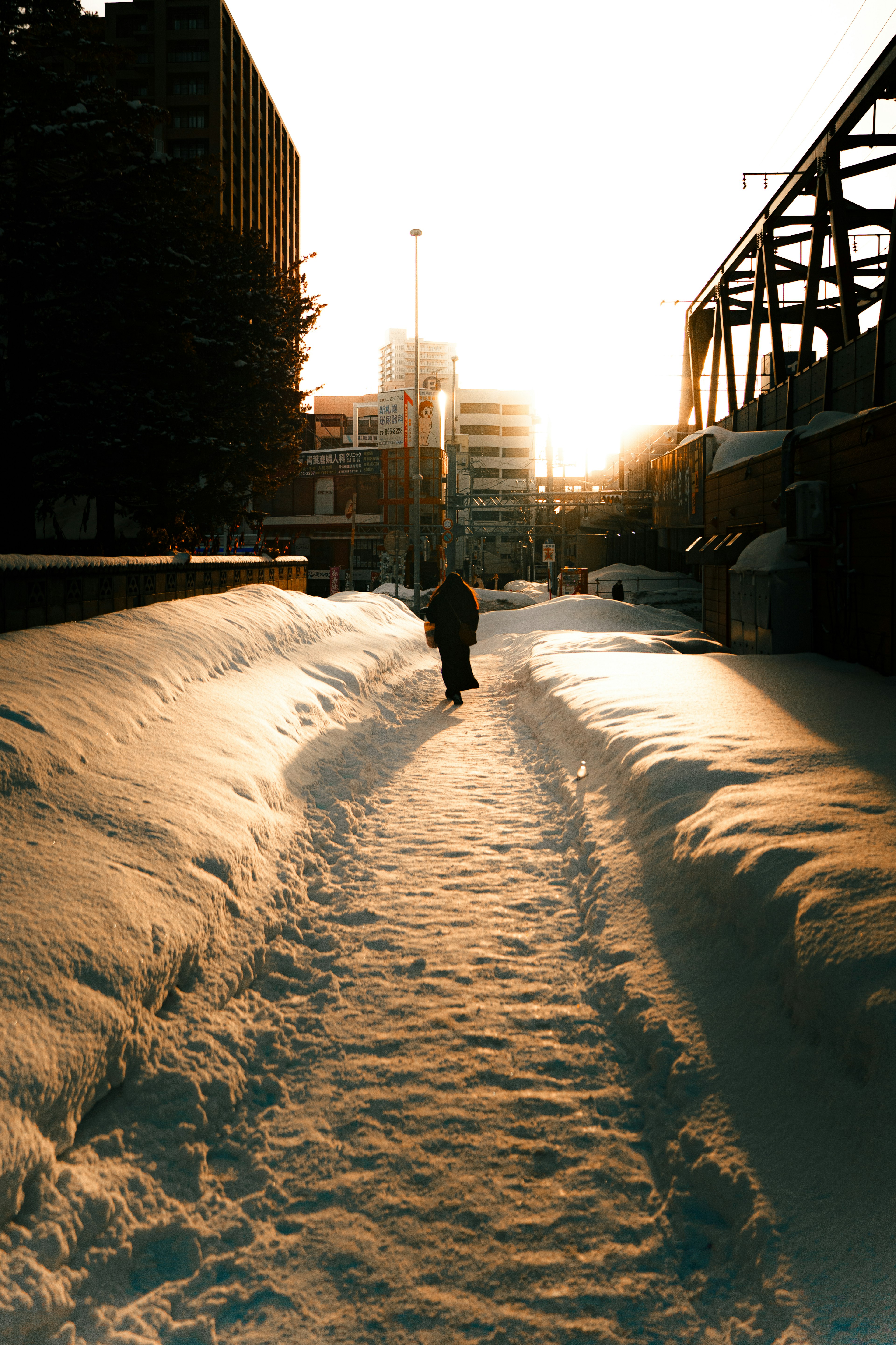 雪に覆われた道を歩く人と背後の夕日