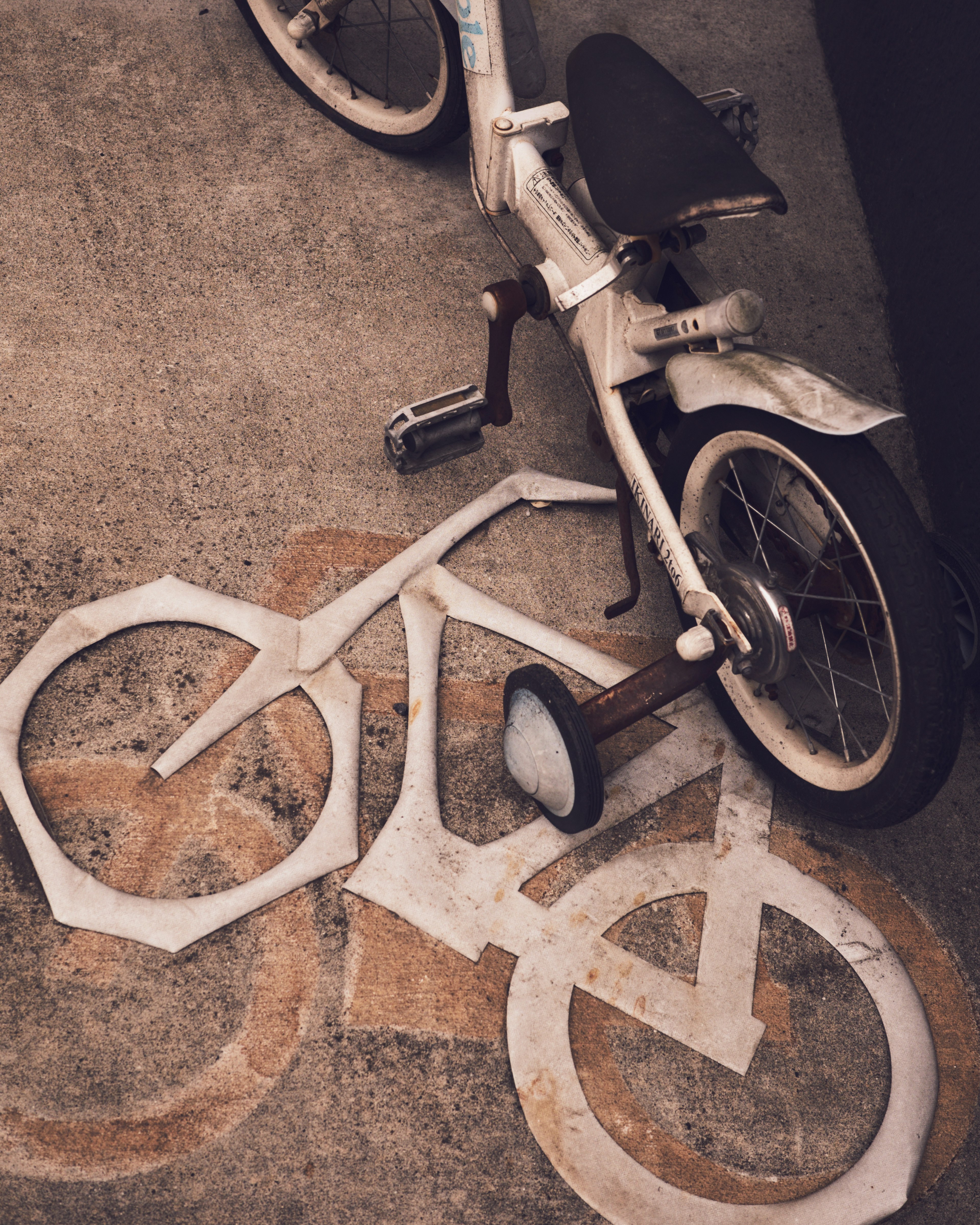 Una bicicletta bianca posizionata su uno stencil di bicicletta a terra