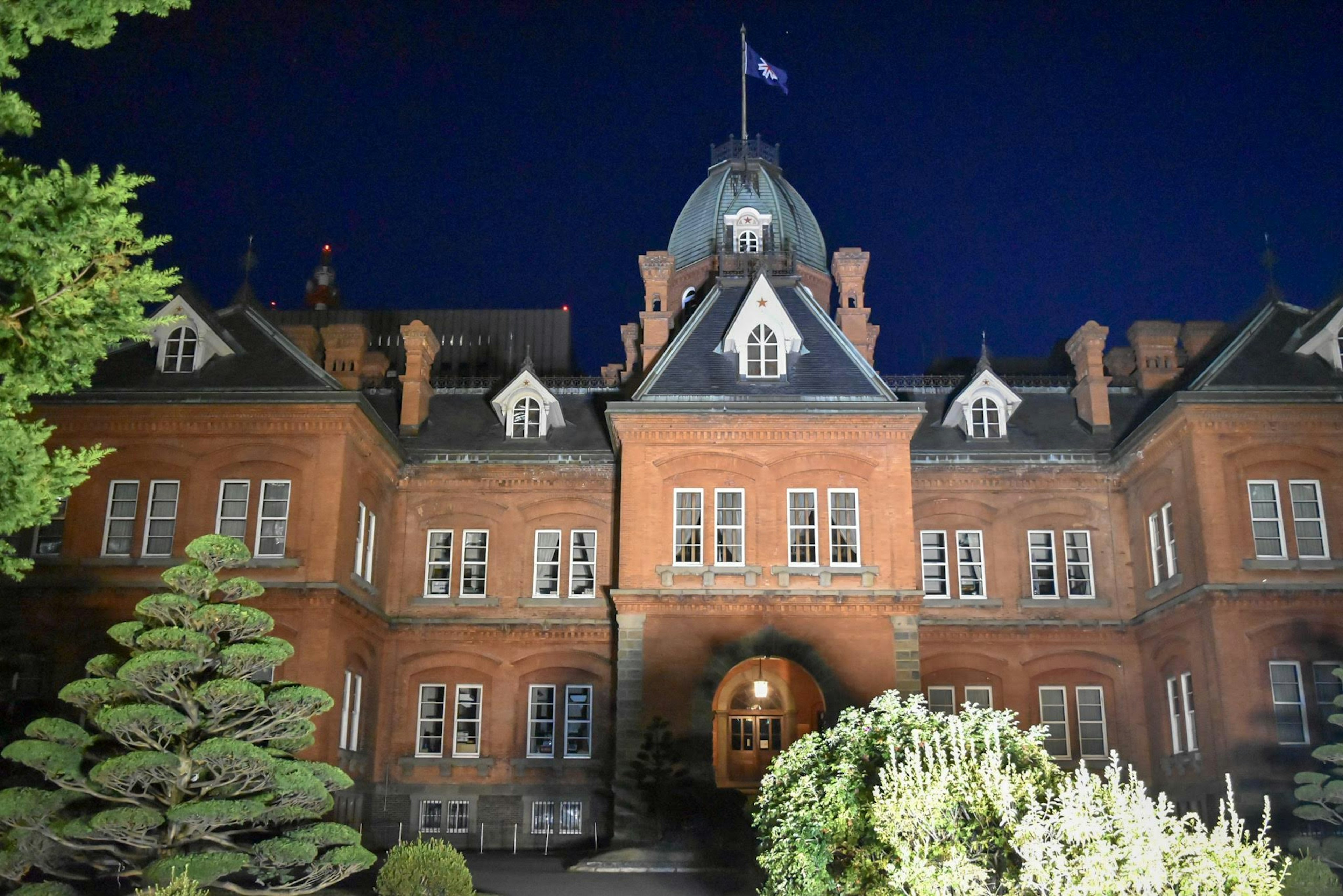 Historic red brick building at night with landscaped garden