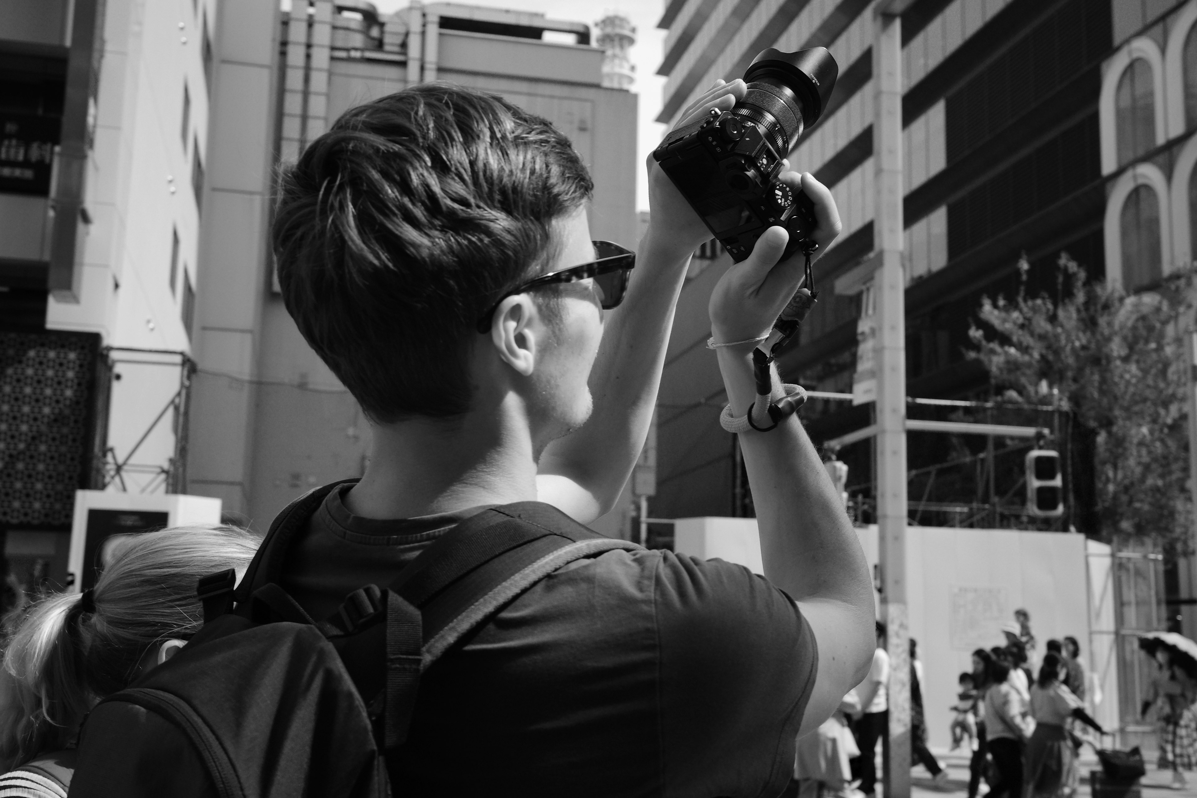 A man holding a camera in a black and white urban setting