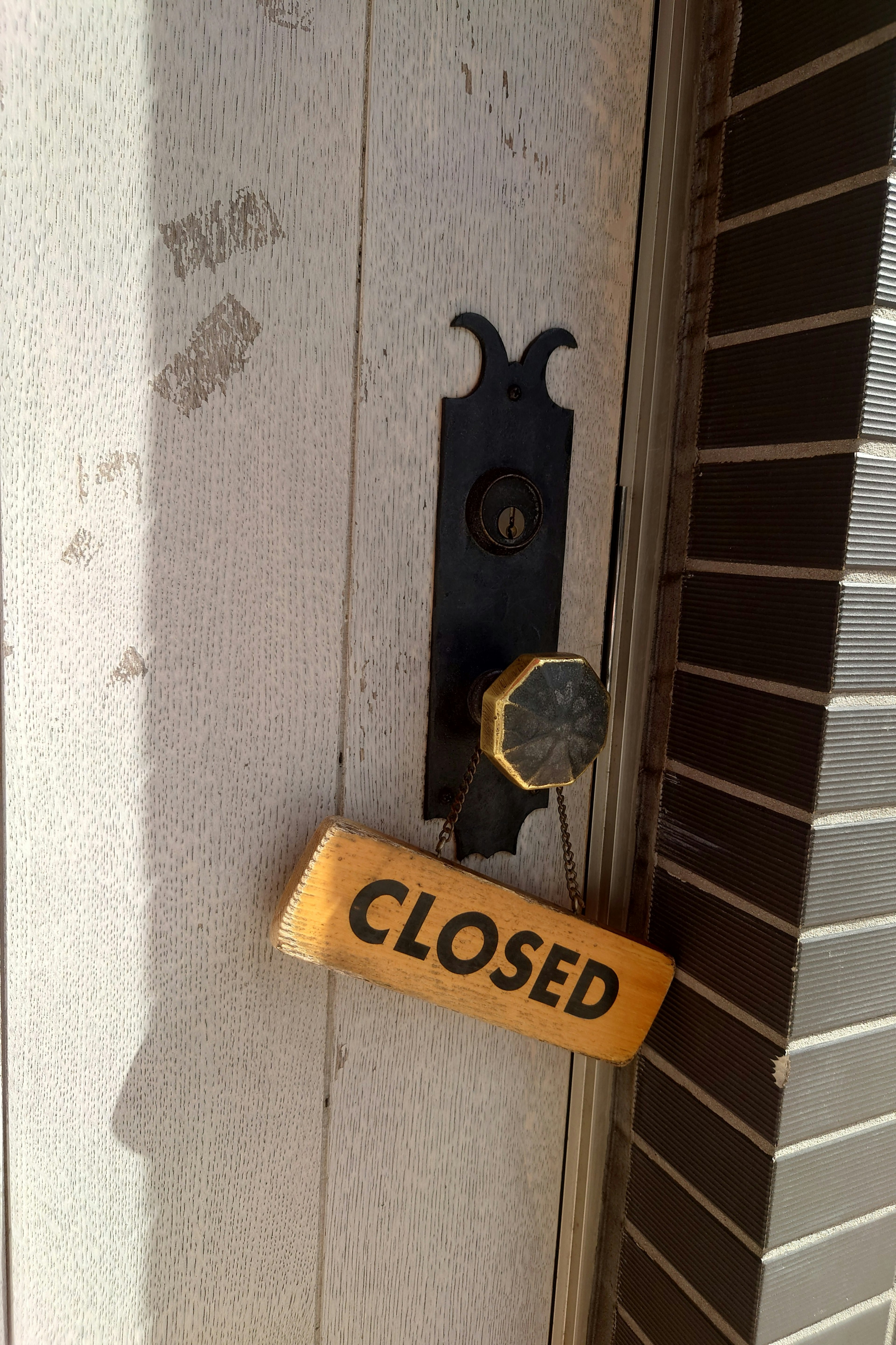 ป้ายไม้ "CLOSED" แขวนอยู่ที่ประตูปิด