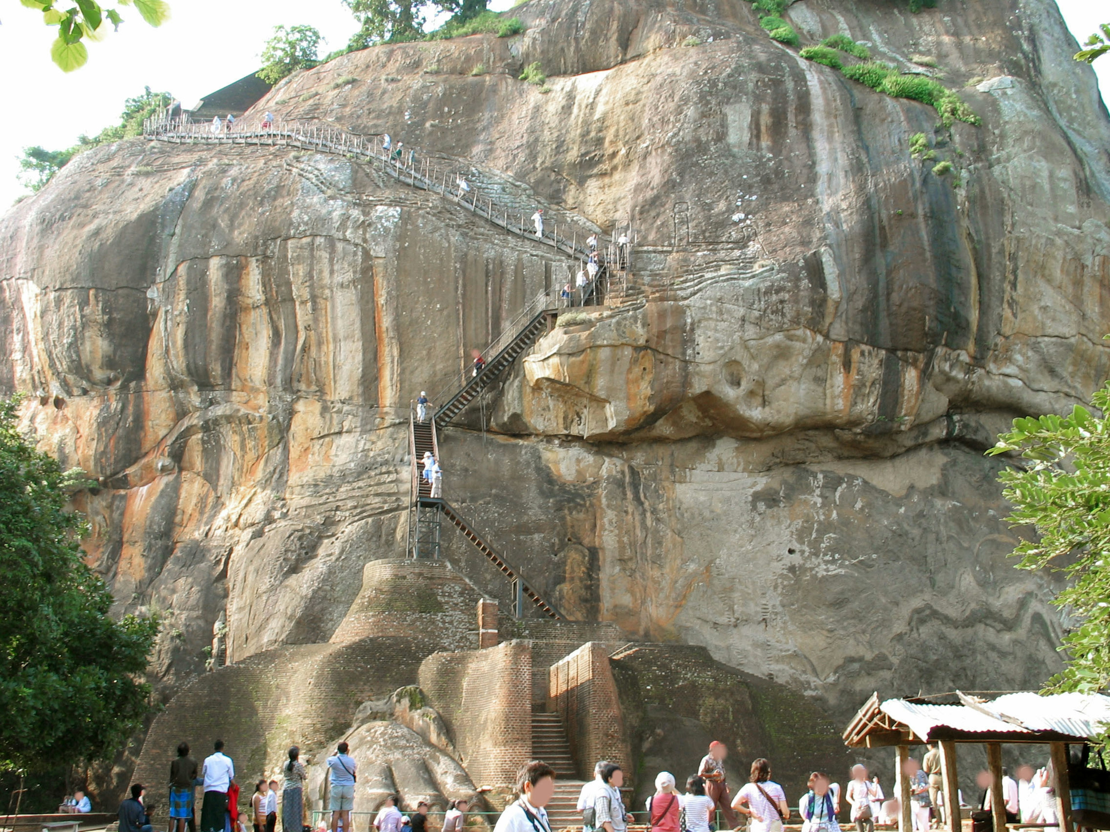 Multitud de turistas subiendo escaleras en una colina rocosa