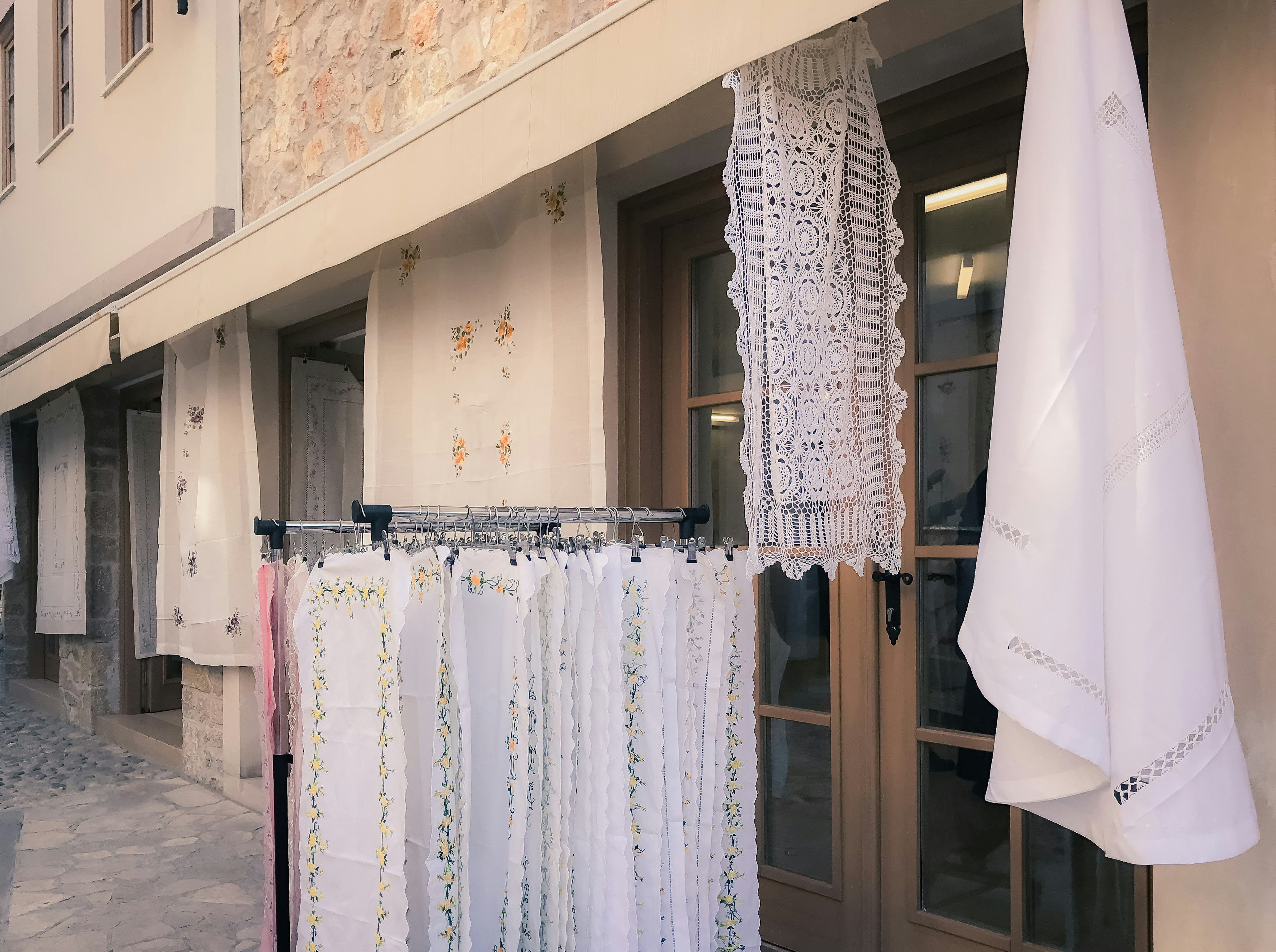 Display of white lace curtains hanging outside a shop