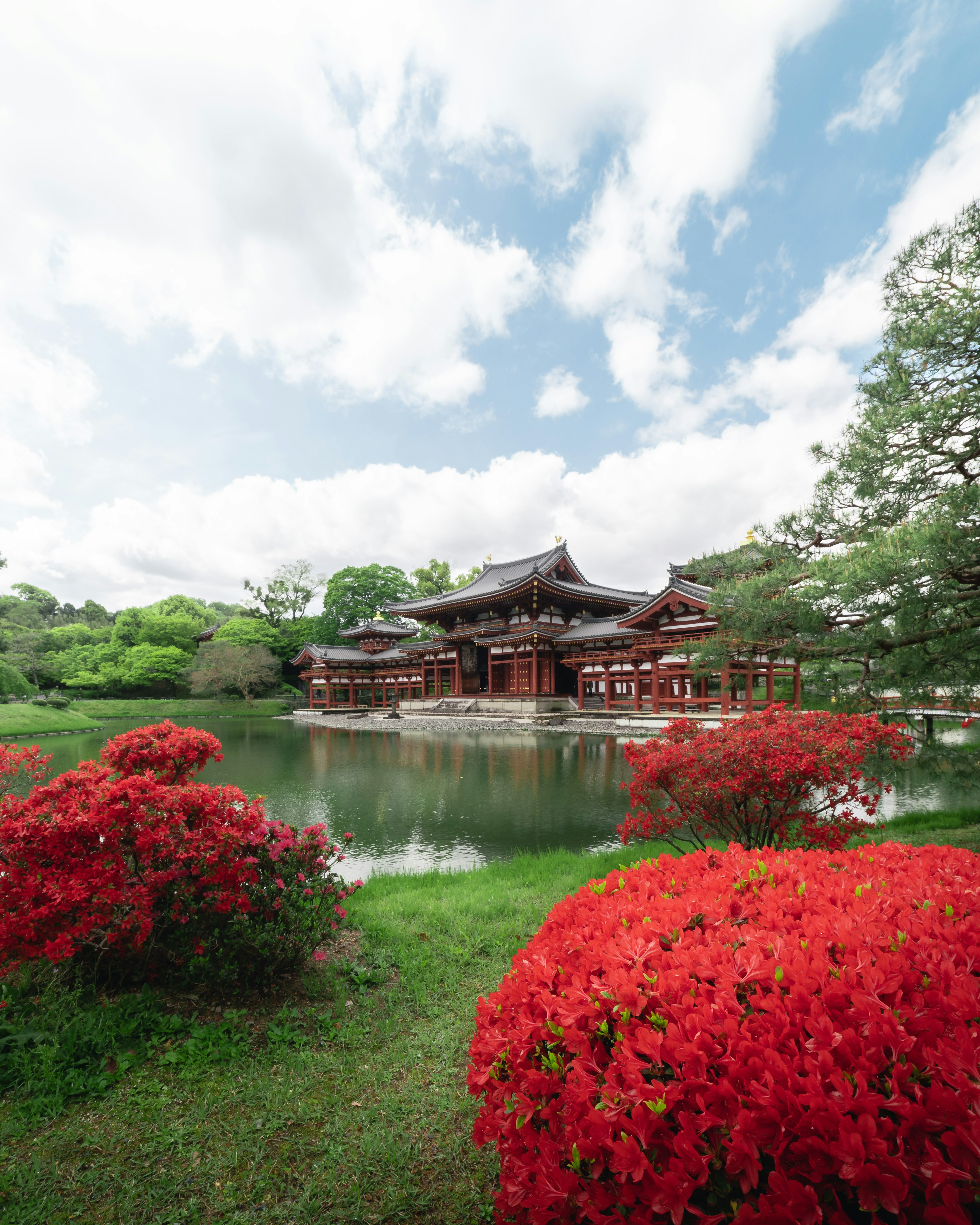 宁静池塘旁的传统建筑，周围环绕着鲜艳的红花