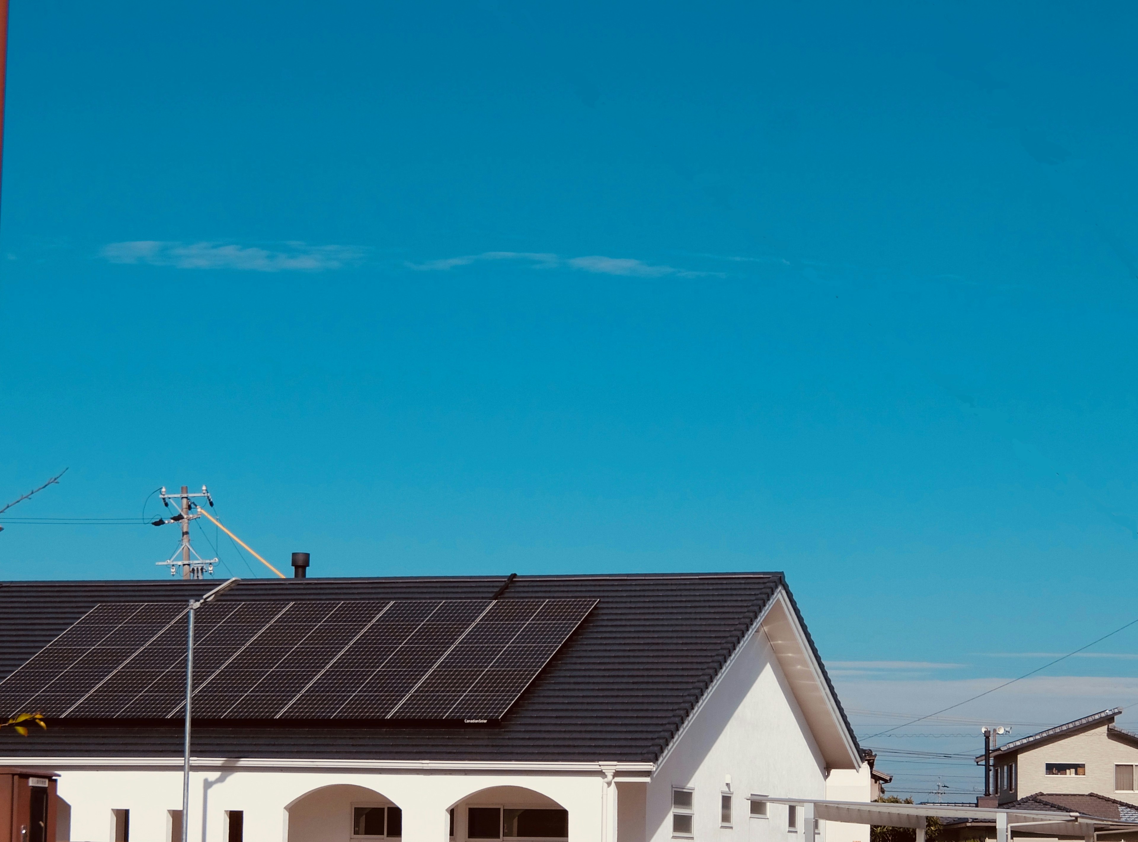 A white house with solar panels under a blue sky