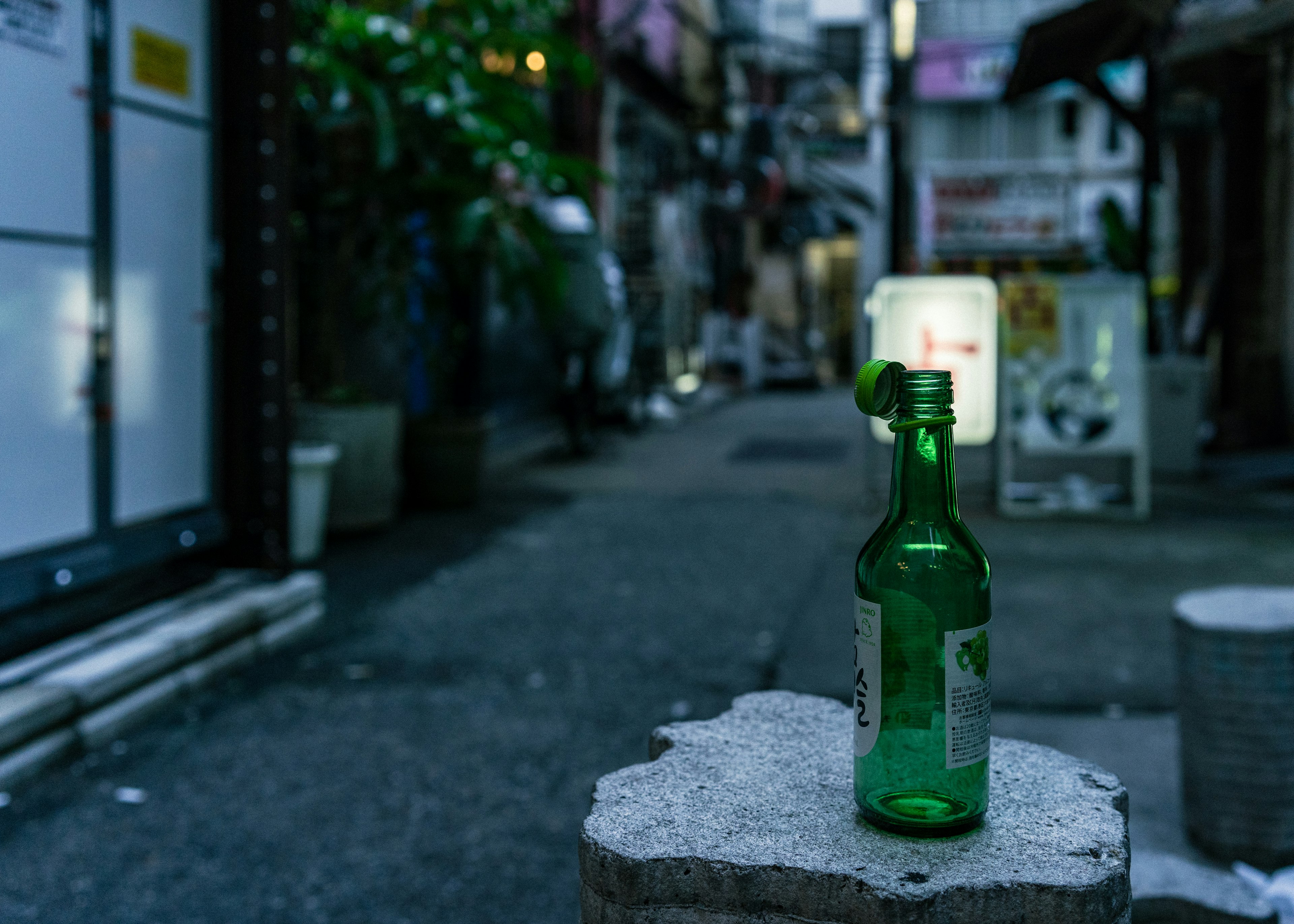 路地に置かれた緑色の瓶と背景のぼやけた店舗