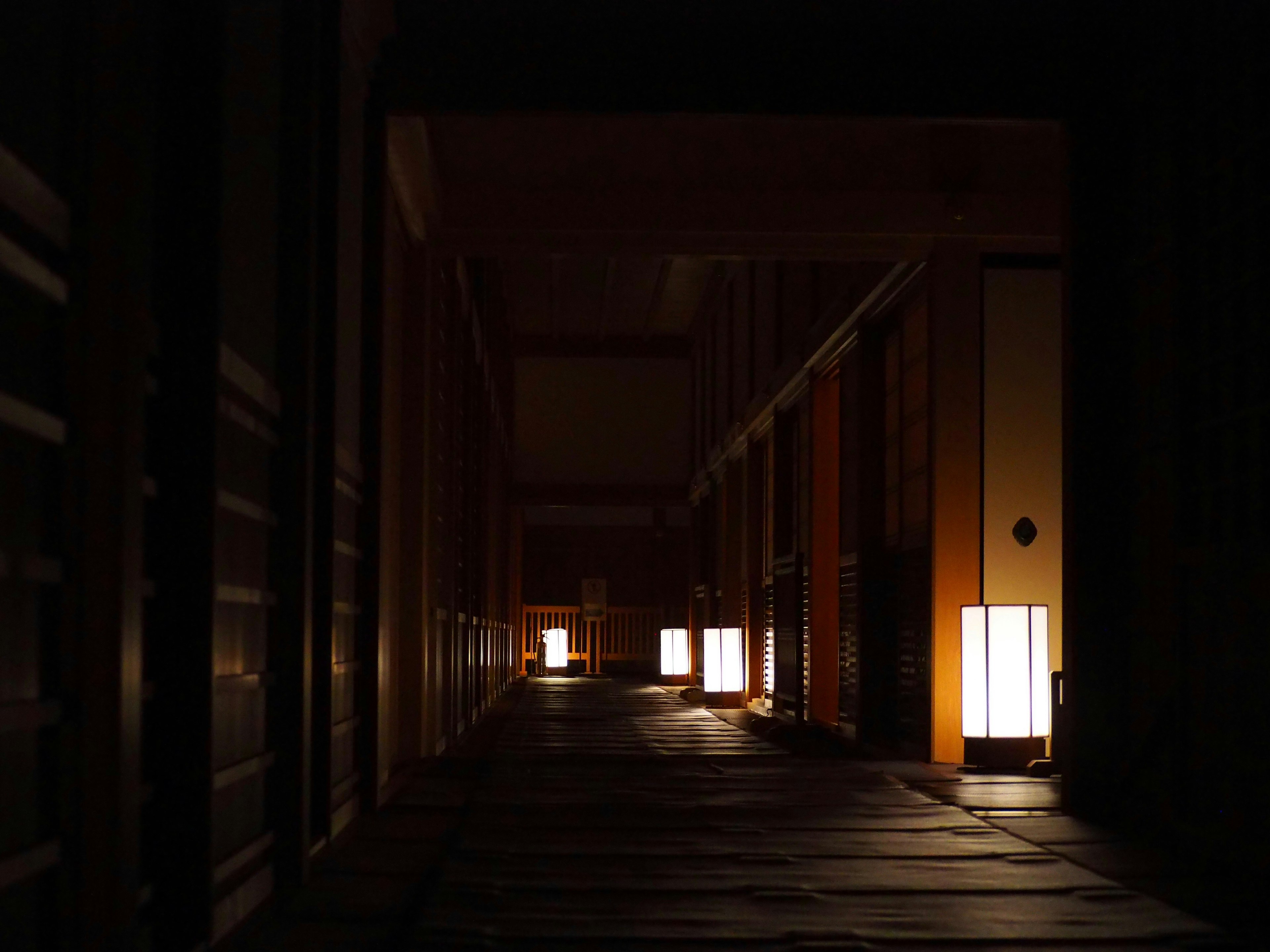 Couloir faiblement éclairé avec des lanternes japonaises traditionnelles diffusant une lumière chaude