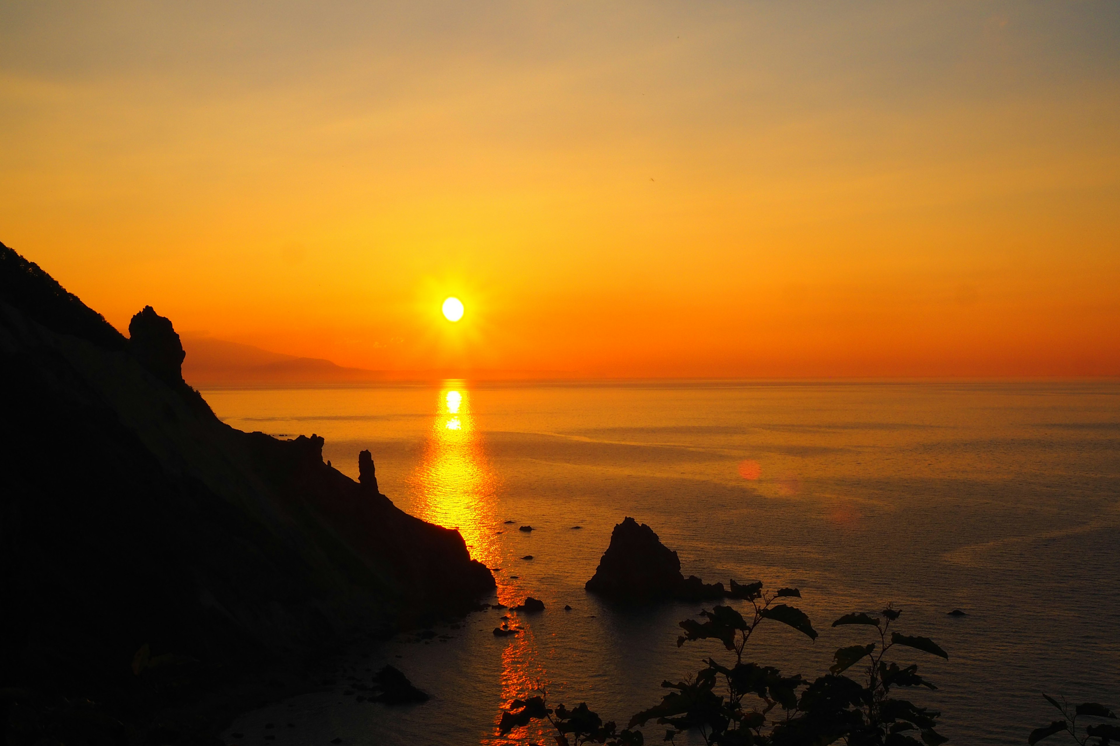 美丽的日落在海面上，前景中有岩石