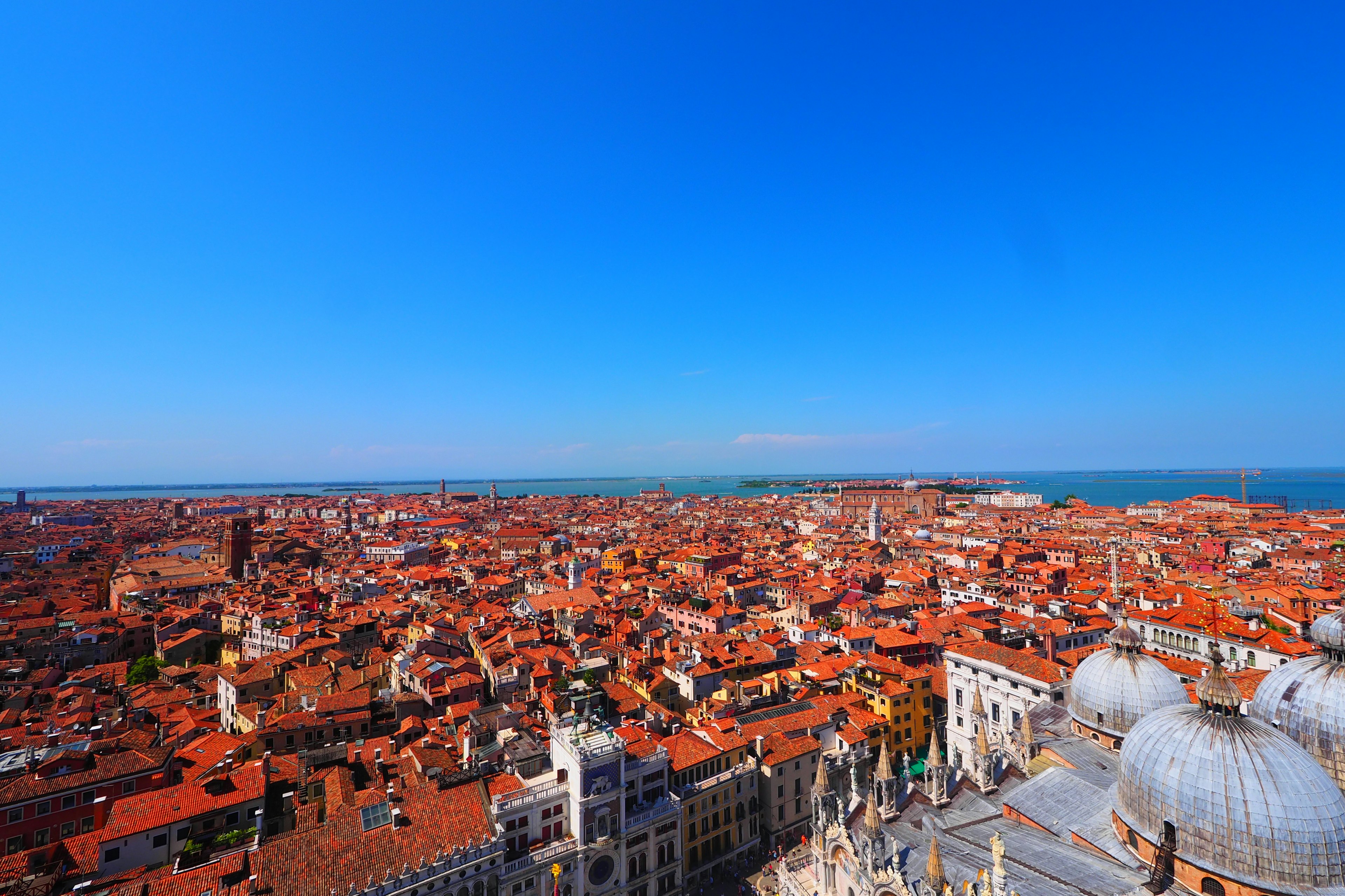 Vista panoramica di Venezia con tetti rossi sotto un cielo blu chiaro