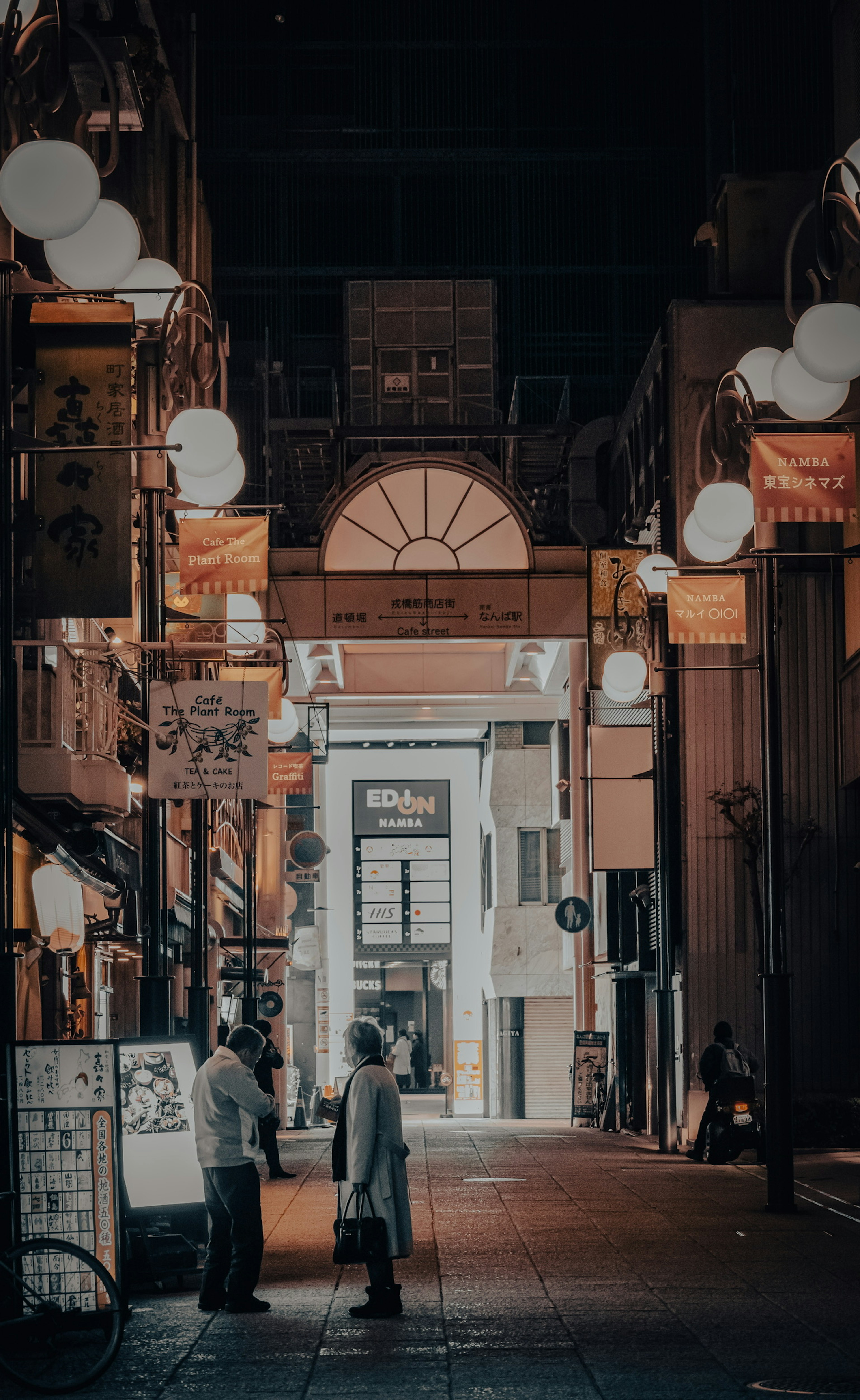 Escena de calle nocturna con personas conversando luces de arcade iluminadas