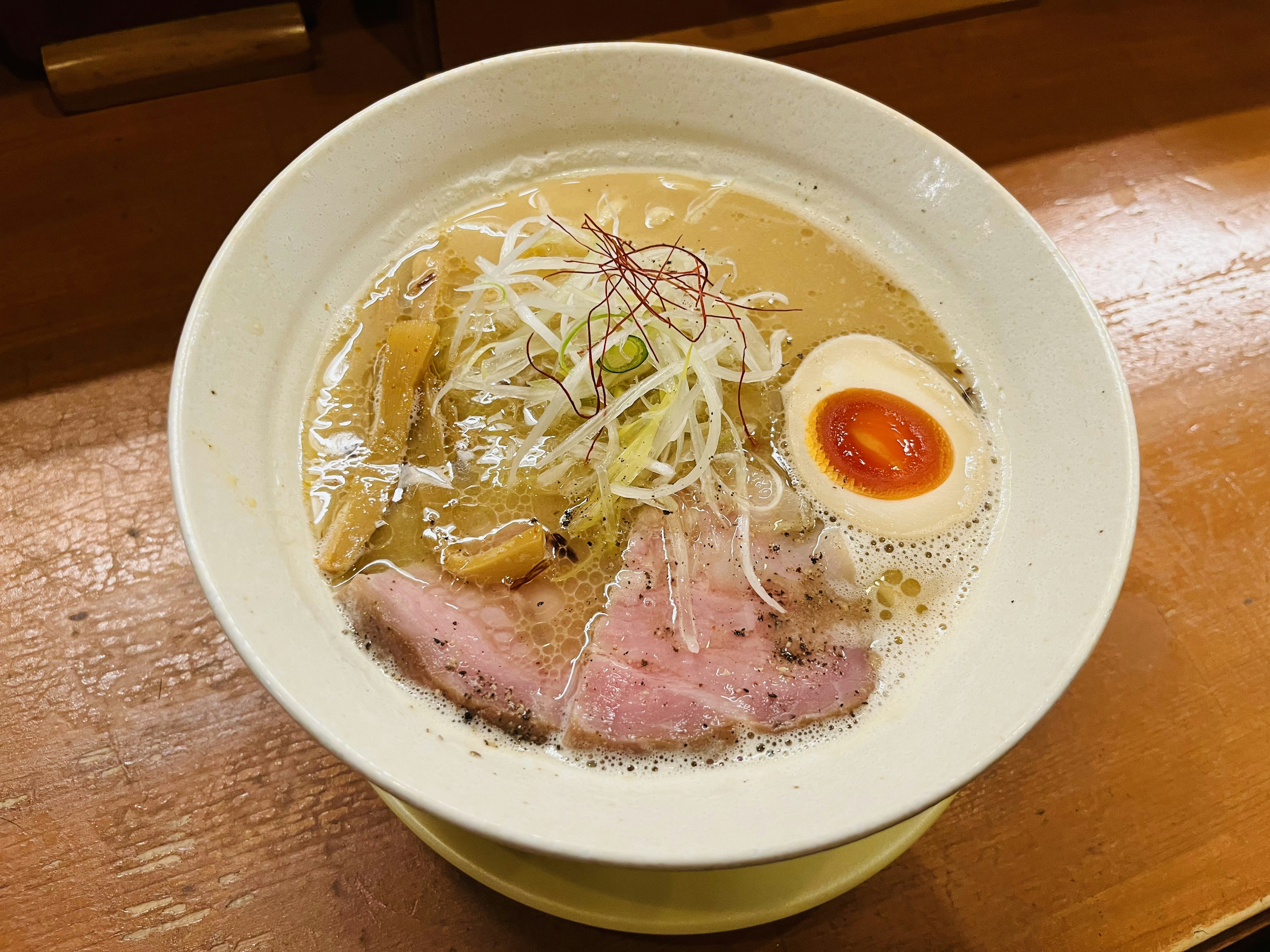 Ramen-Schüssel mit cremiger Brühe, belegt mit geschnittenem Schweinefleisch und weichgekochtem Ei